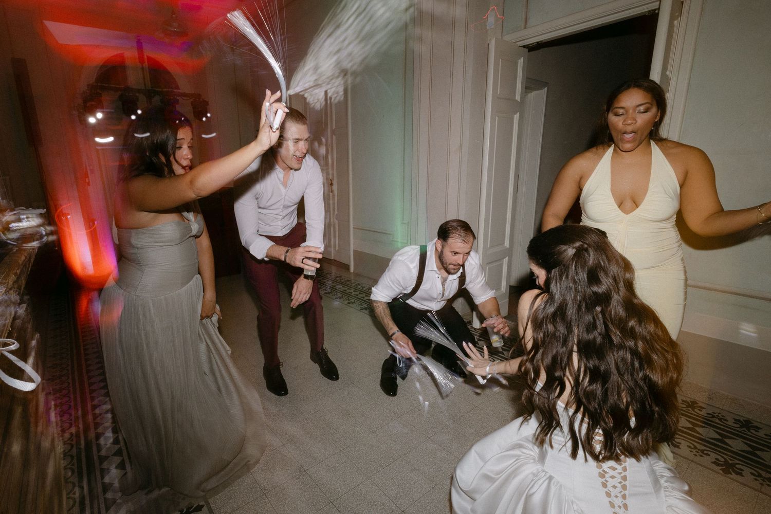 Energetic wedding reception dance floor with guests celebrating under colorful party lights.