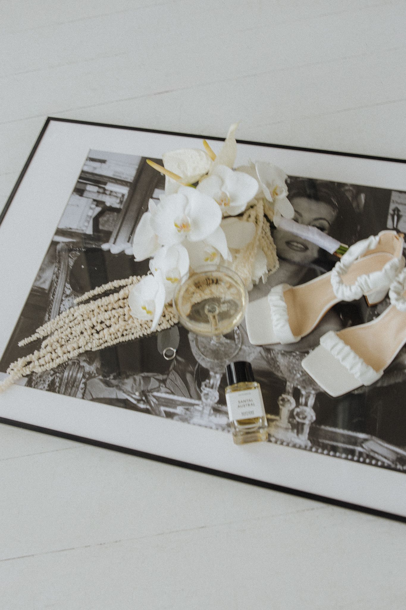 Vintage black and white photographs with white flowers and jewelry scattered on top creating an artistic arrangement.