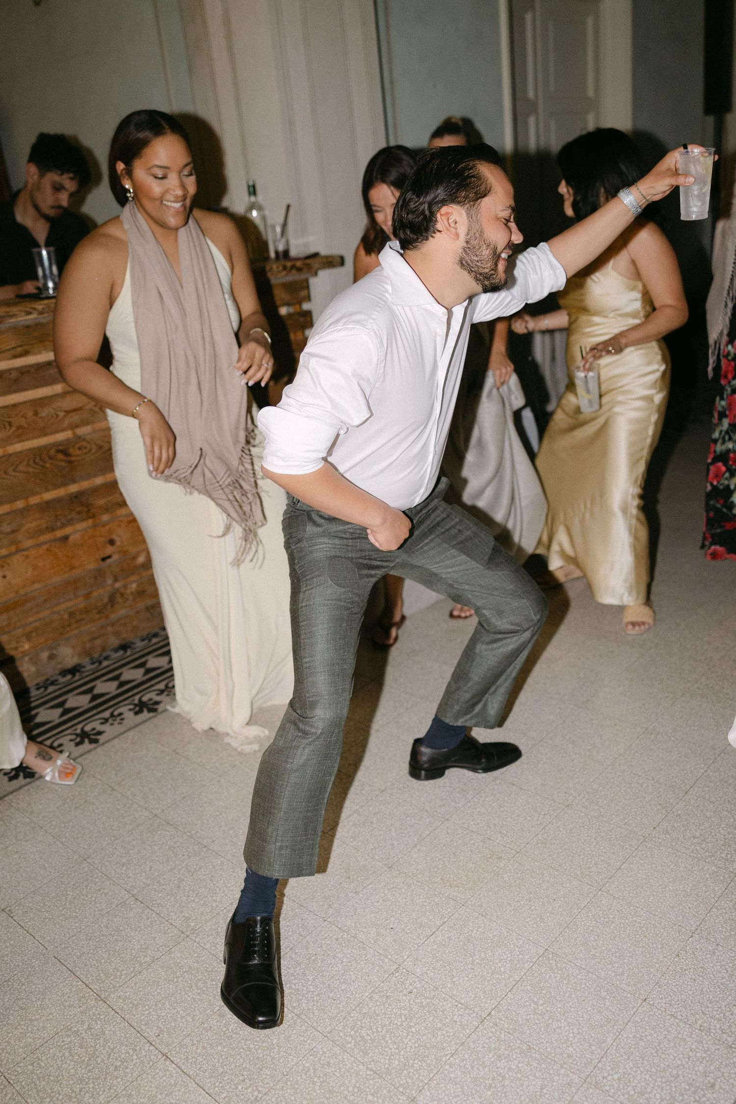 Energetic wedding guest in white shirt dancing enthusiastically on the reception dance floor with other guests.