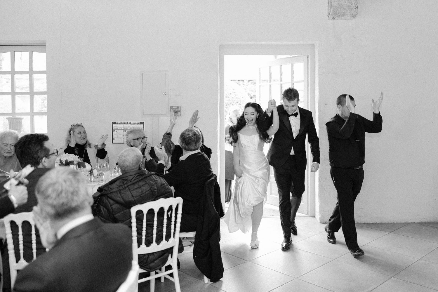 Black and white photo of bride and groom making a grand entrance into the wedding reception hall.