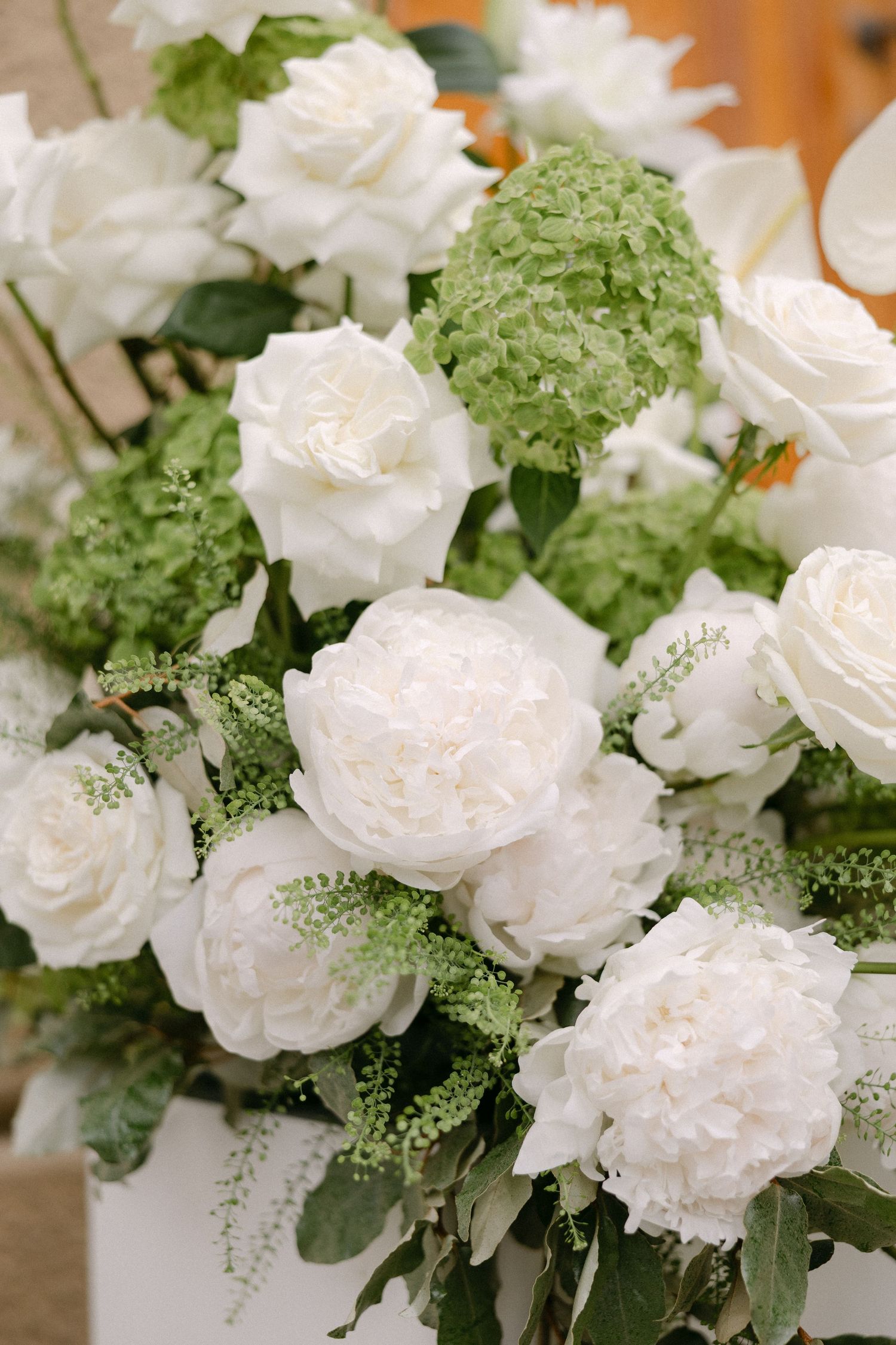 Elegant wedding floral arrangement featuring white peonies, roses, and green hydrangeas.