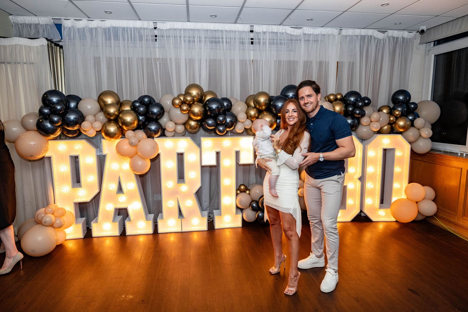 Party venue with illuminated letter signs and balloon arch decorations.