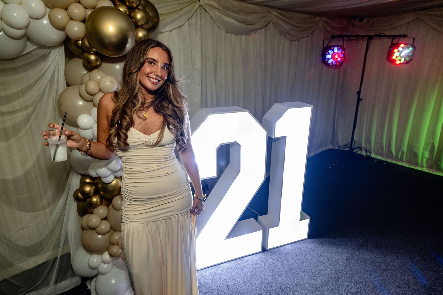 Event space with gold and white balloon decorations and illuminated numbers.
