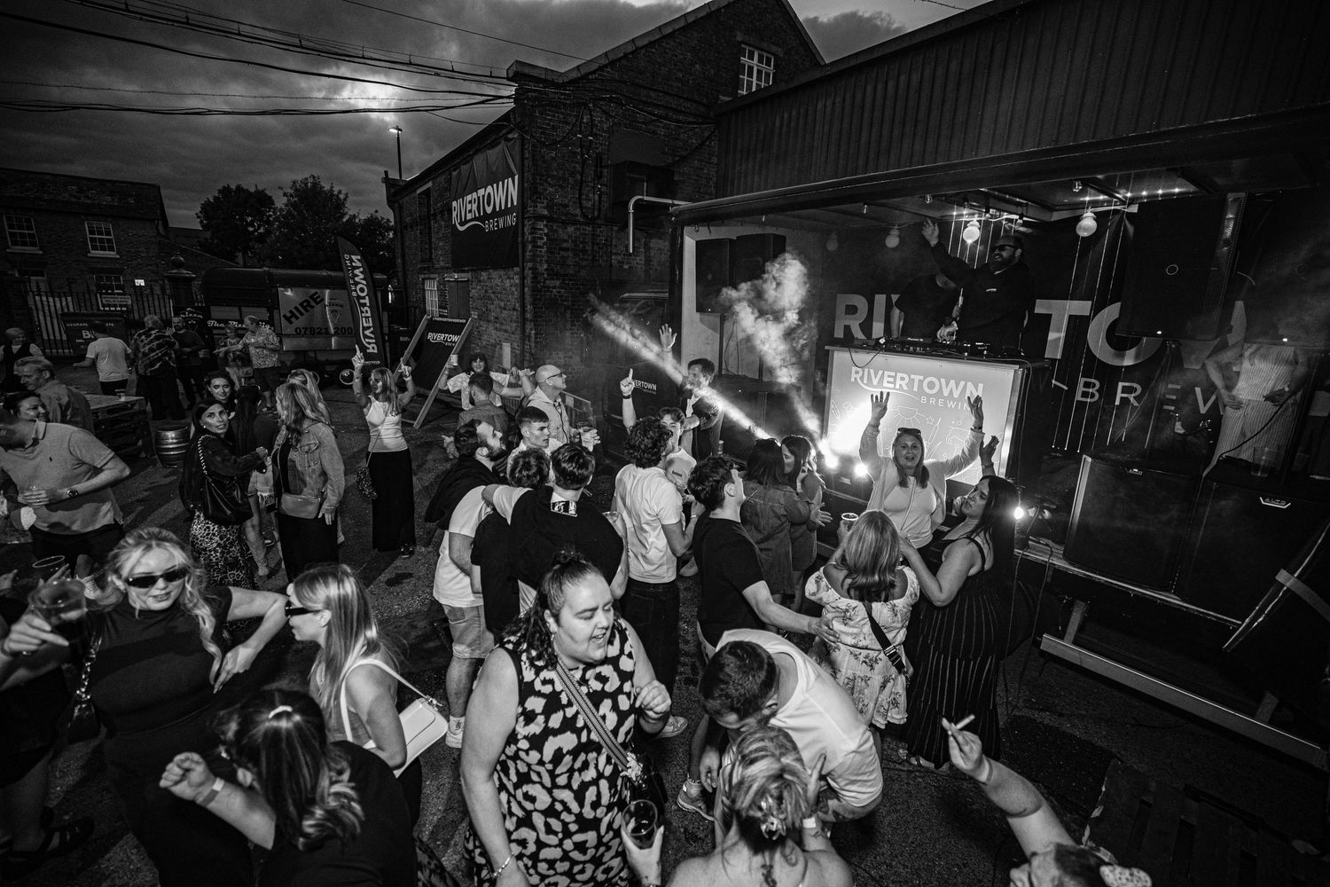 A black and white photo of an energetic crowd dancing at a nighttime party venue.