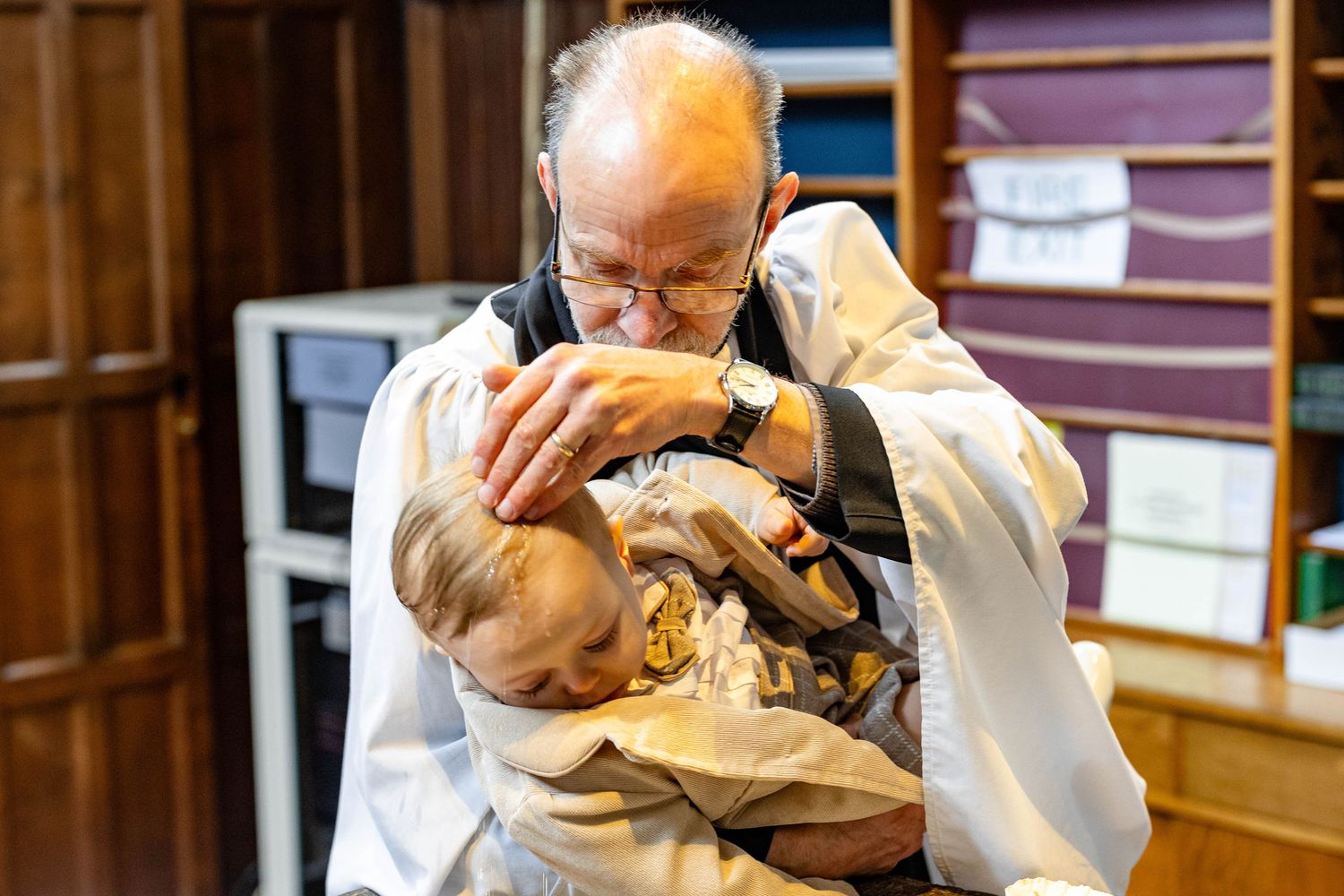 A tender moment during a religious baptism ceremony in a church setting.