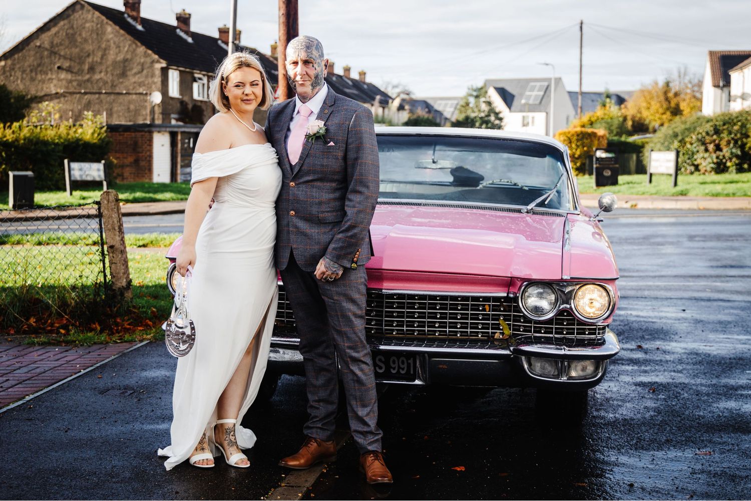Classic pink Cadillac parked outside serves as elegant wedding transportation on rainy day.