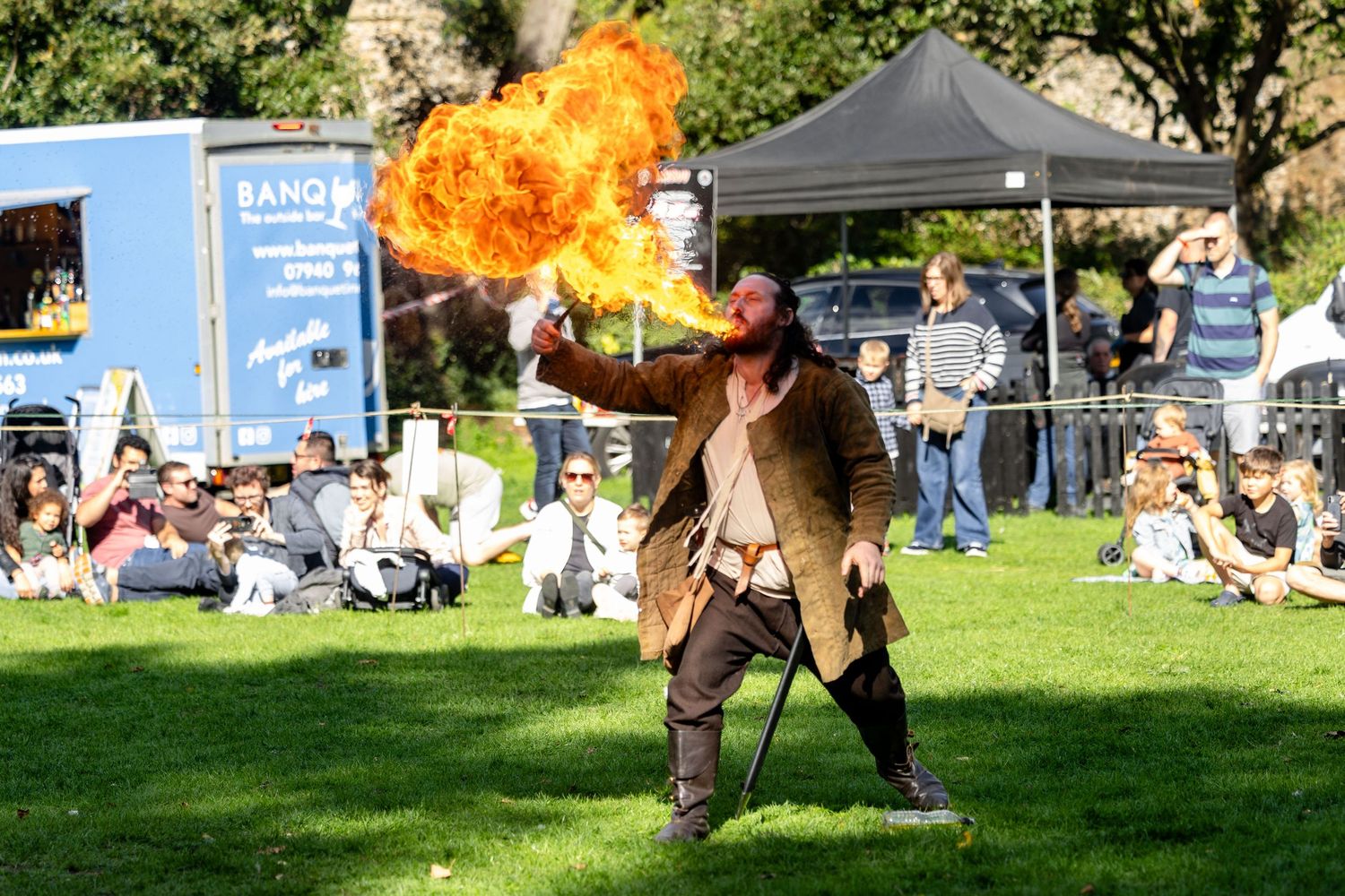 A fire performer creating dramatic flame effects at an outdoor event.