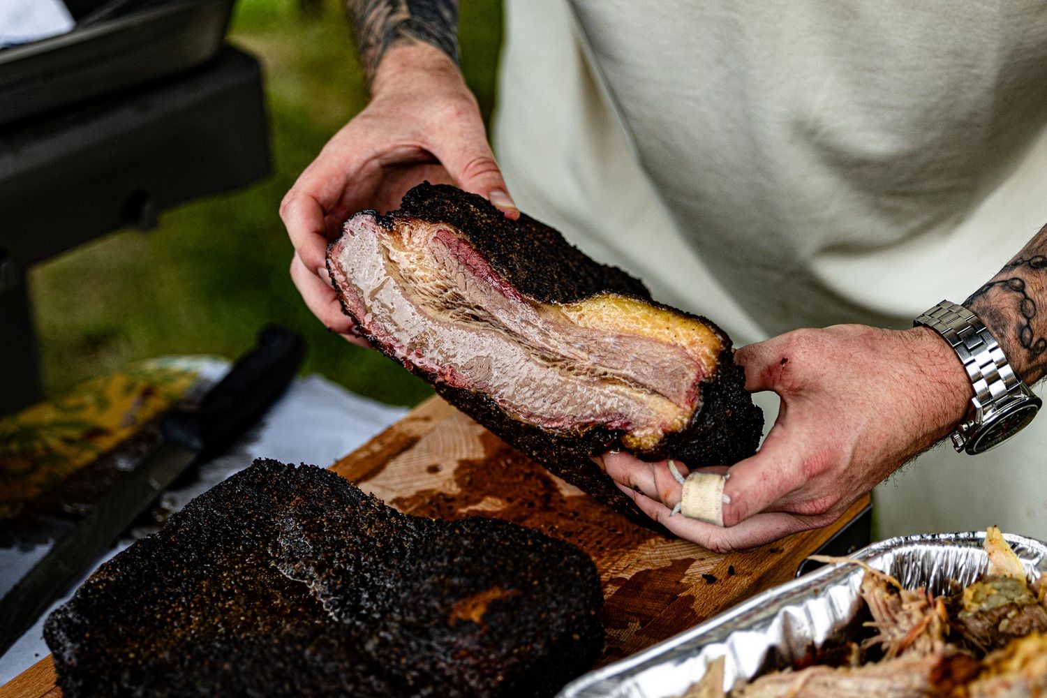 A series of hands slicing and preparing smoked brisket on a wooden cutting board.