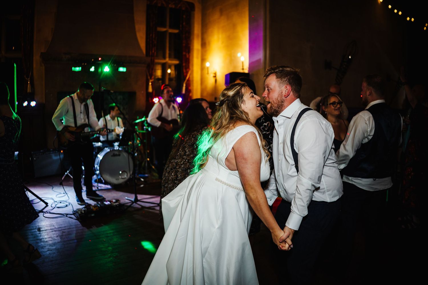 Bride and groom share a romantic kiss on the dance floor while a live band performs at their wedding reception.