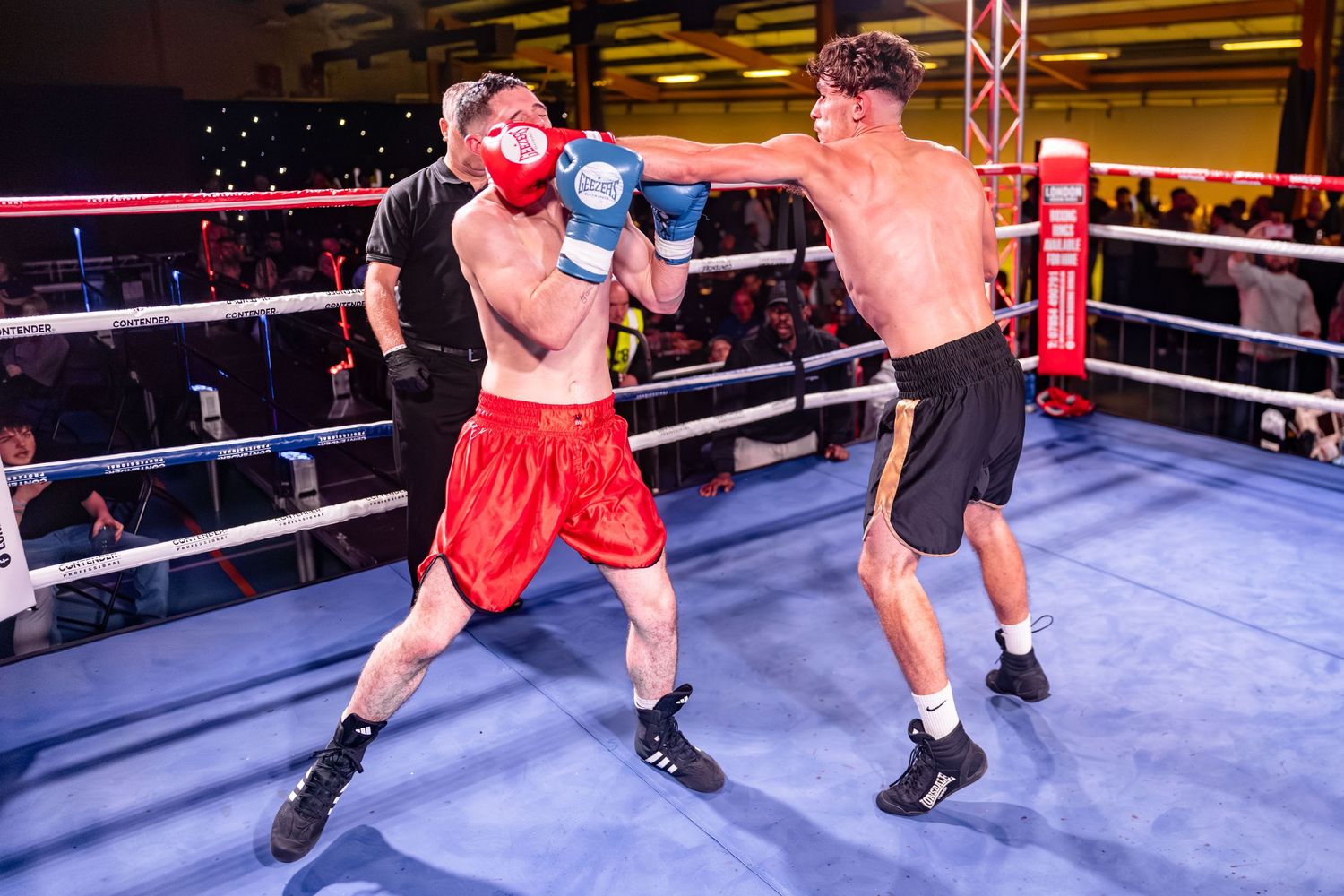 Two kickboxers exchange powerful strikes during an intense match in a professional boxing ring.