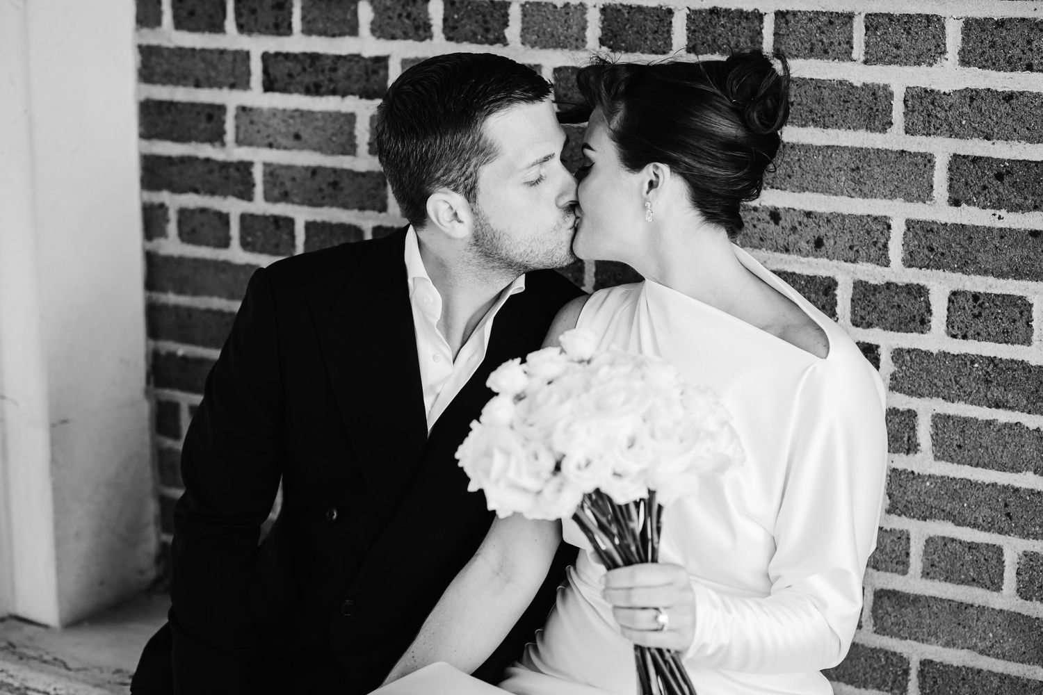 An intimate moment shared between a couple against a brick wall backdrop.