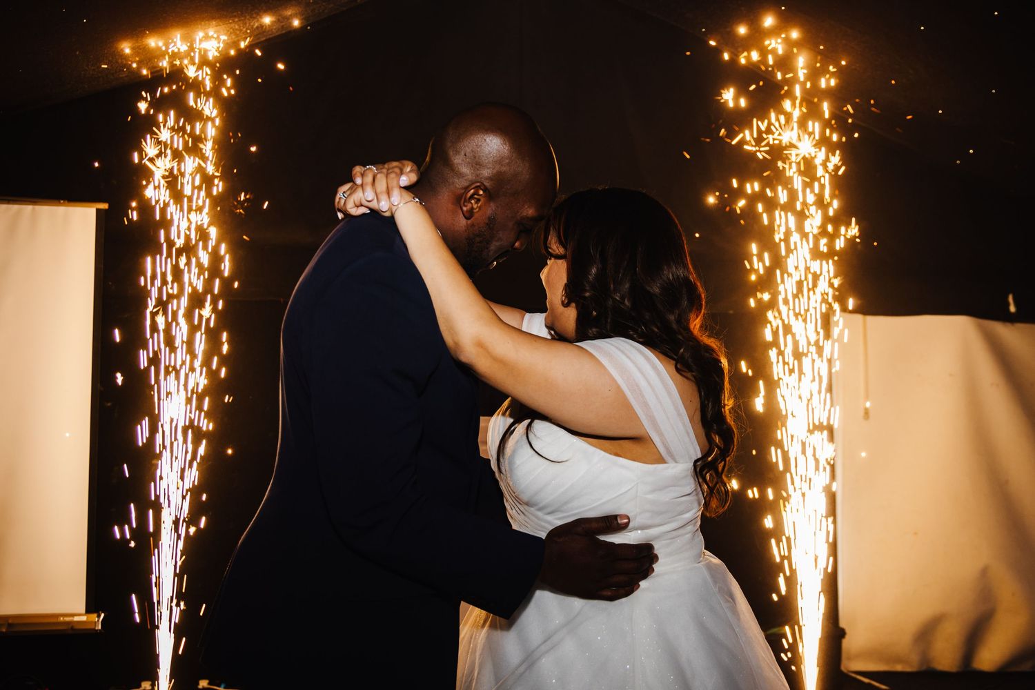 First dance at wedding reception with dramatic sparkler fountains in background.