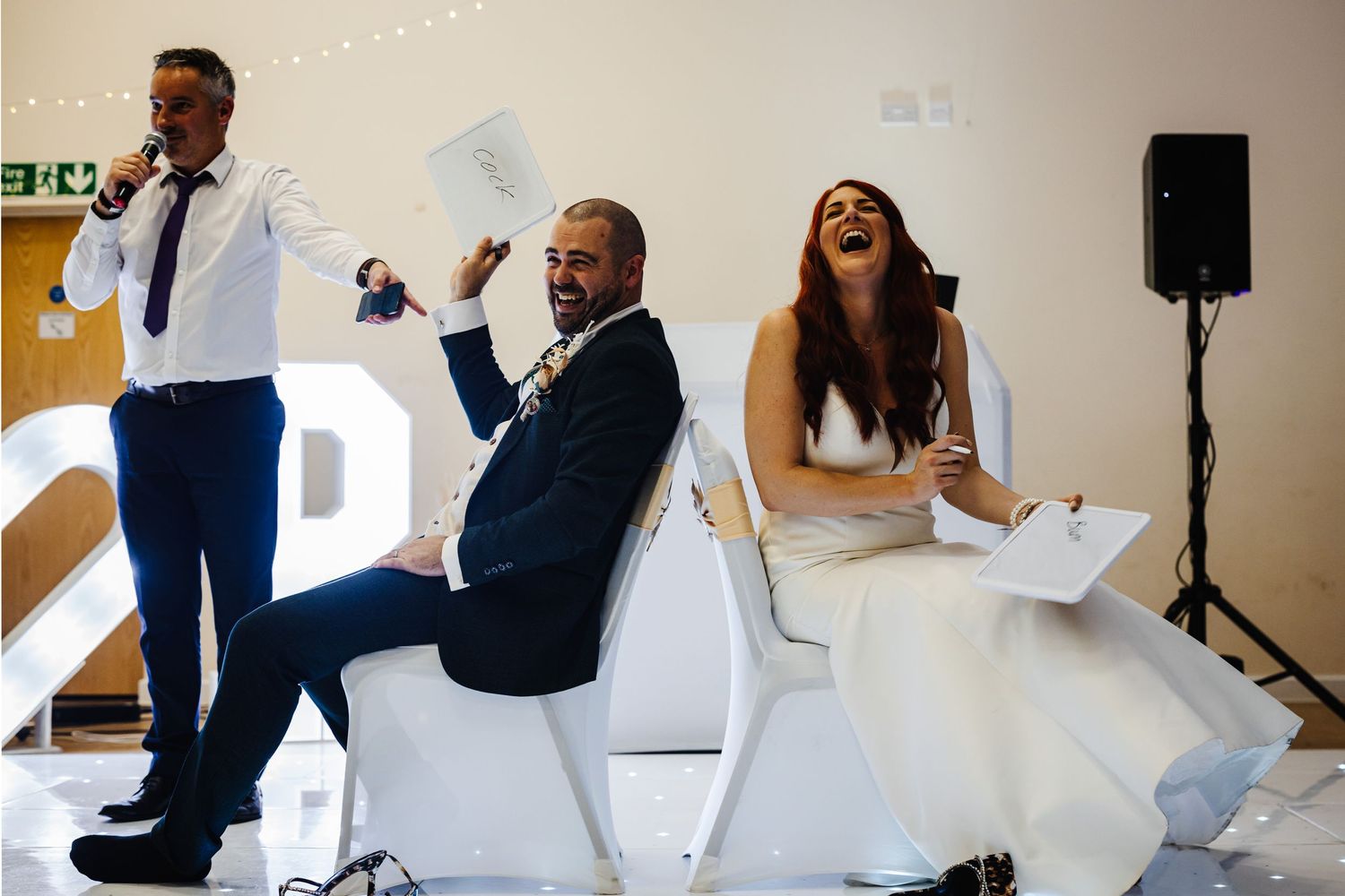 Wedding guests share a joyful moment of laughter during reception speeches at an elegant venue.
