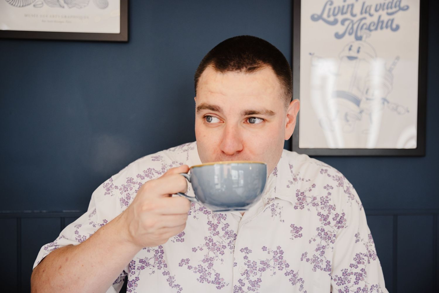 A casual moment with a gray coffee mug against a navy blue wall with framed artwork.