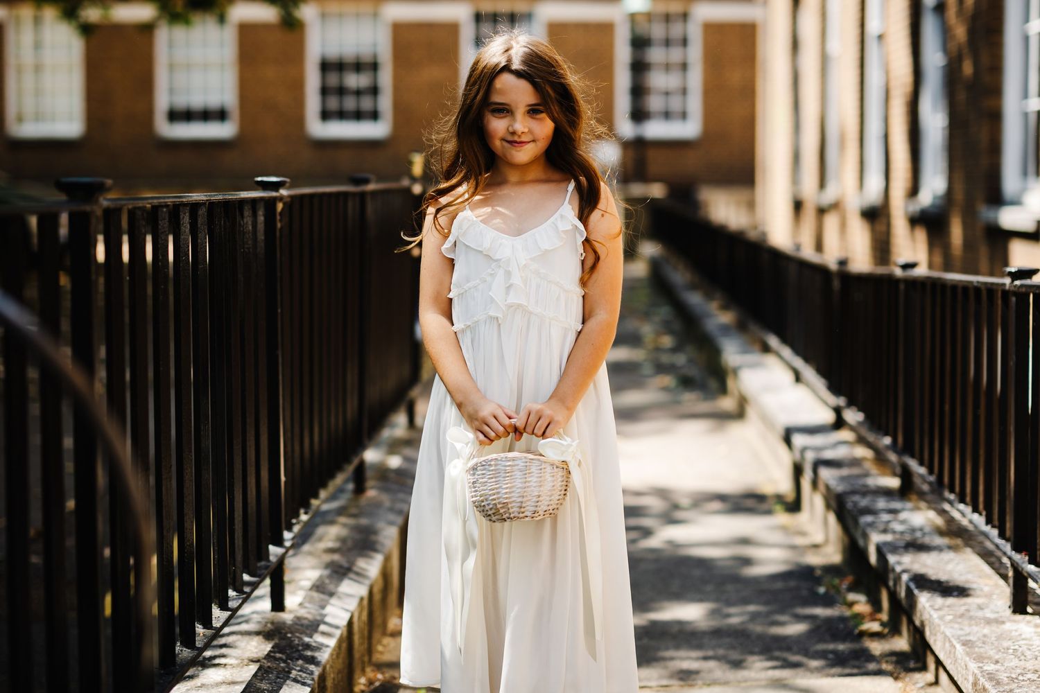 A white dress with lace details photographed on an urban balcony with iron railings.