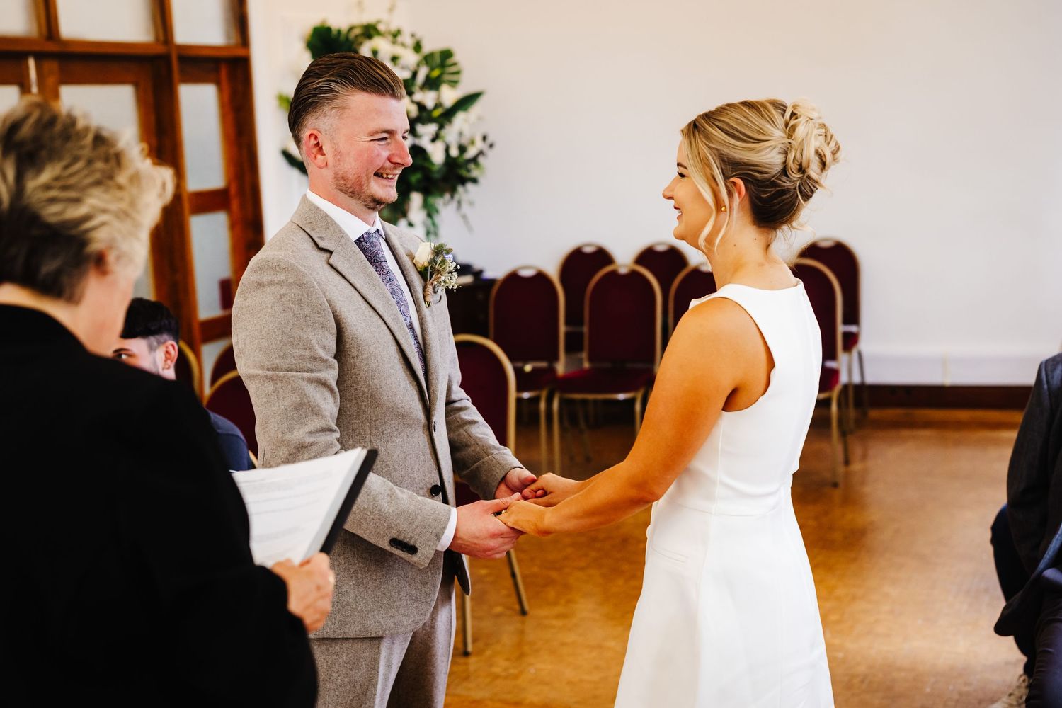 A wedding ceremony in progress inside a bright indoor venue with wooden details.