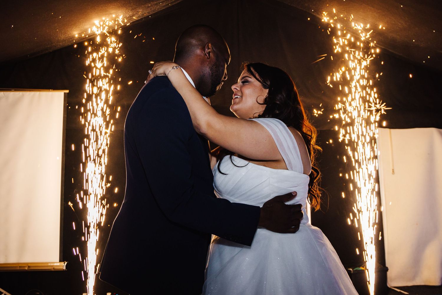 A couple shares their first dance as newlyweds with dramatic sparkler fountains illuminating the romantic moment.