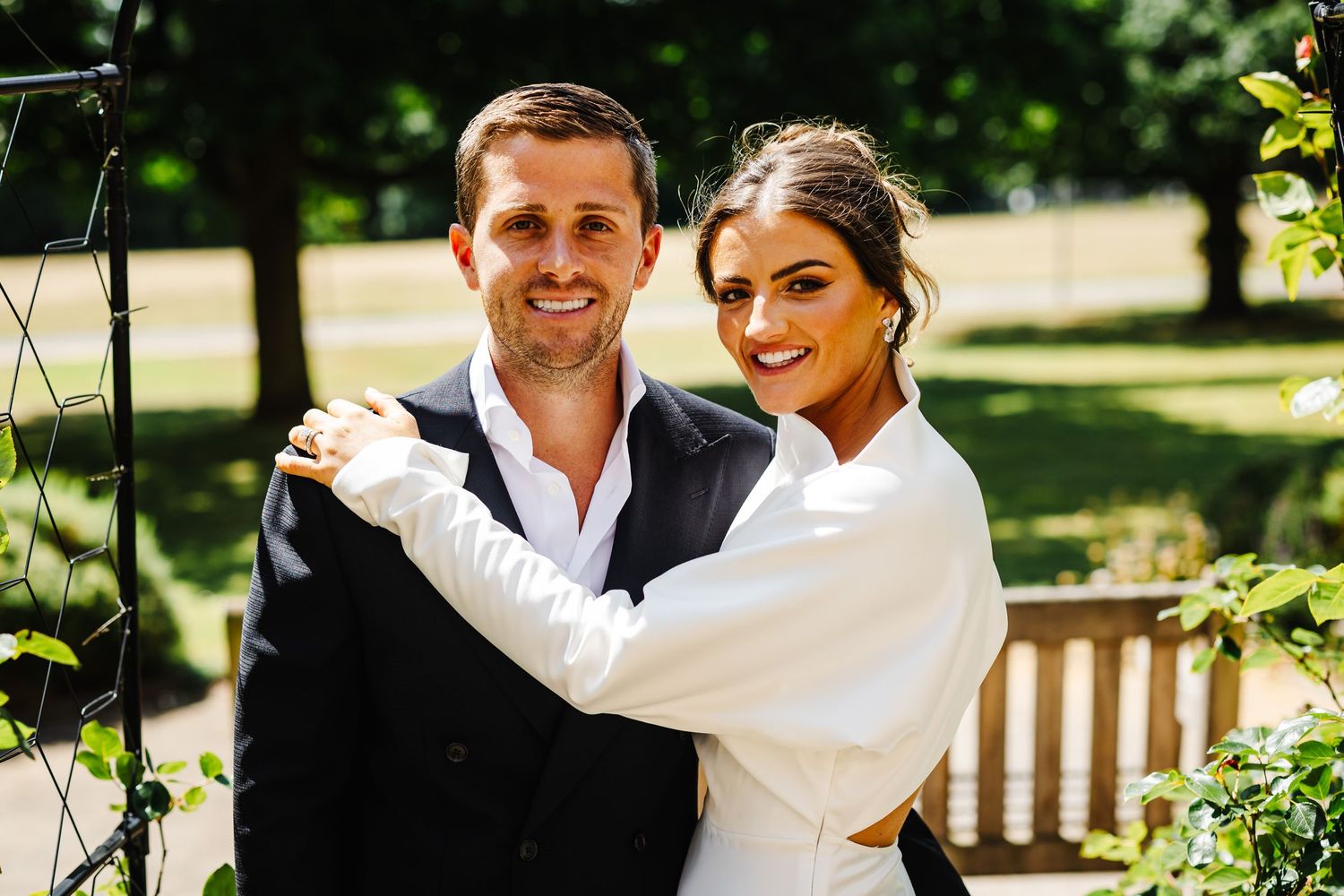 A joyful outdoor wedding photoshoot in a sunny garden setting.