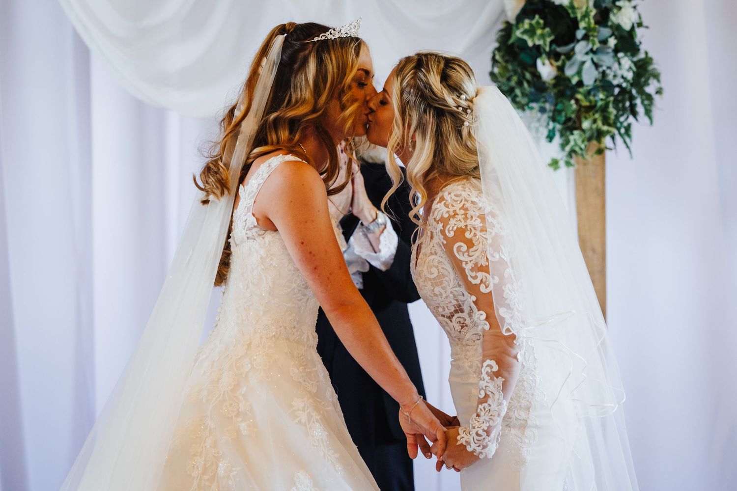 Wedding couple sharing intimate moment against white backdrop with floral decor.