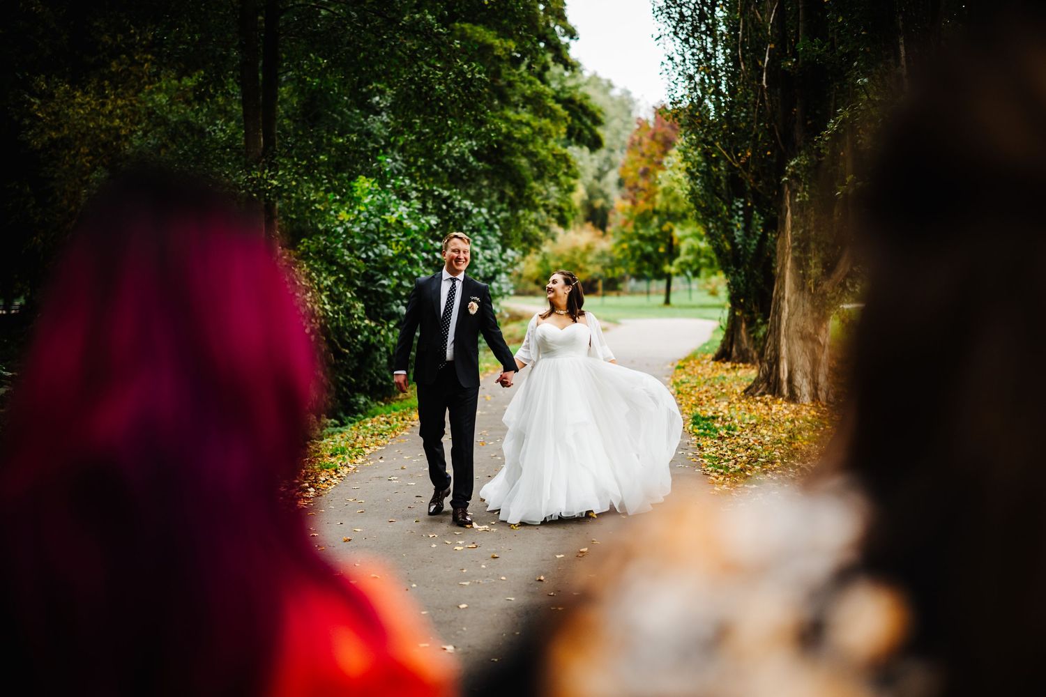 Wedding party walks along a scenic wooded path during an autumn photo session.