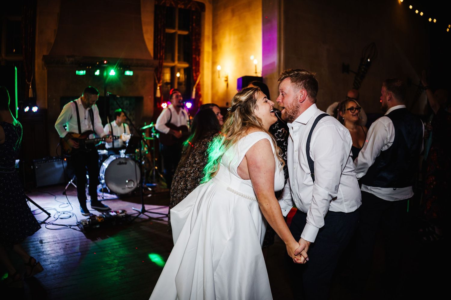 A couple shares their first dance at a wedding reception with colorful lights illuminating the dance floor.