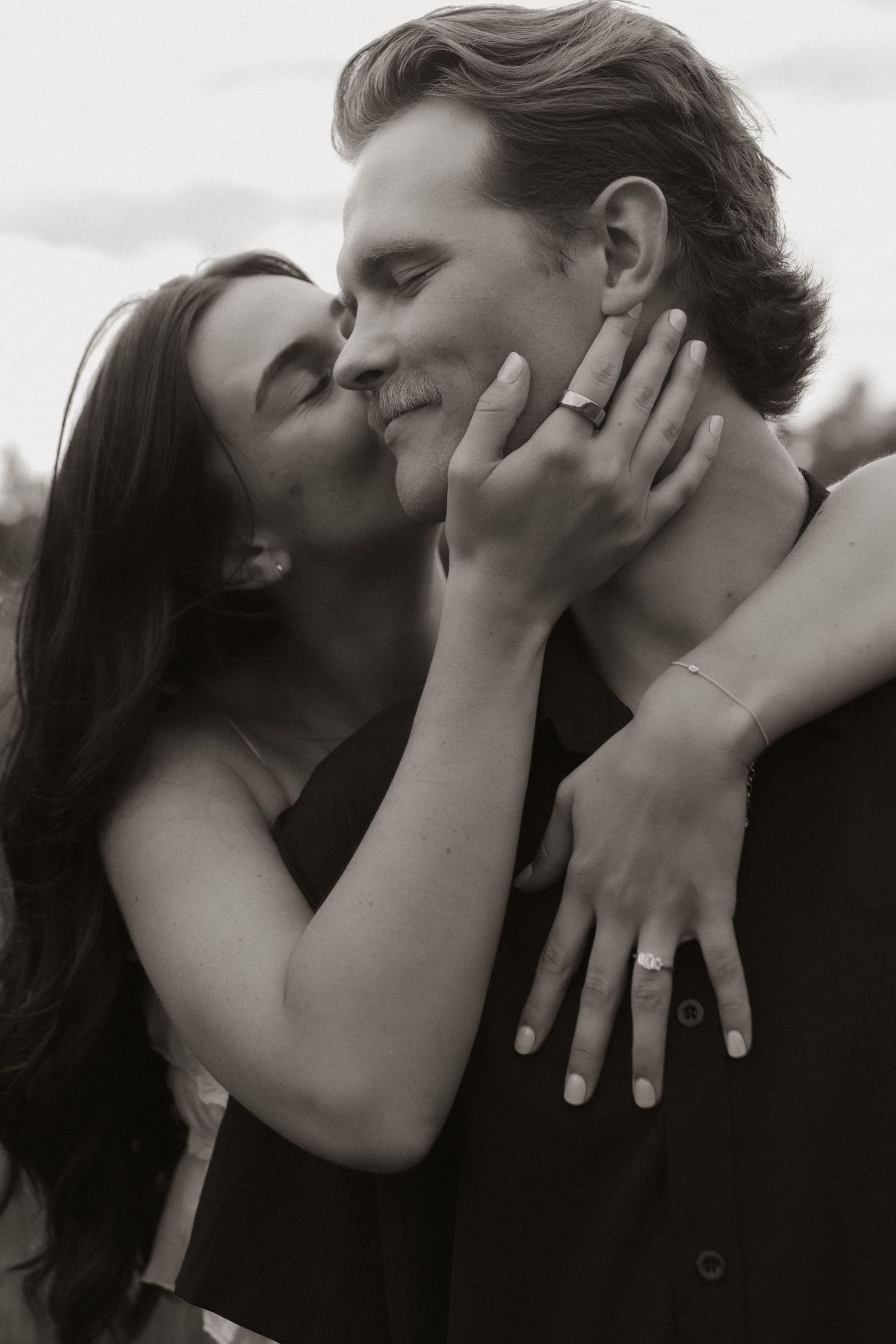 An intimate black and white portrait of a couple sharing a tender moment.
