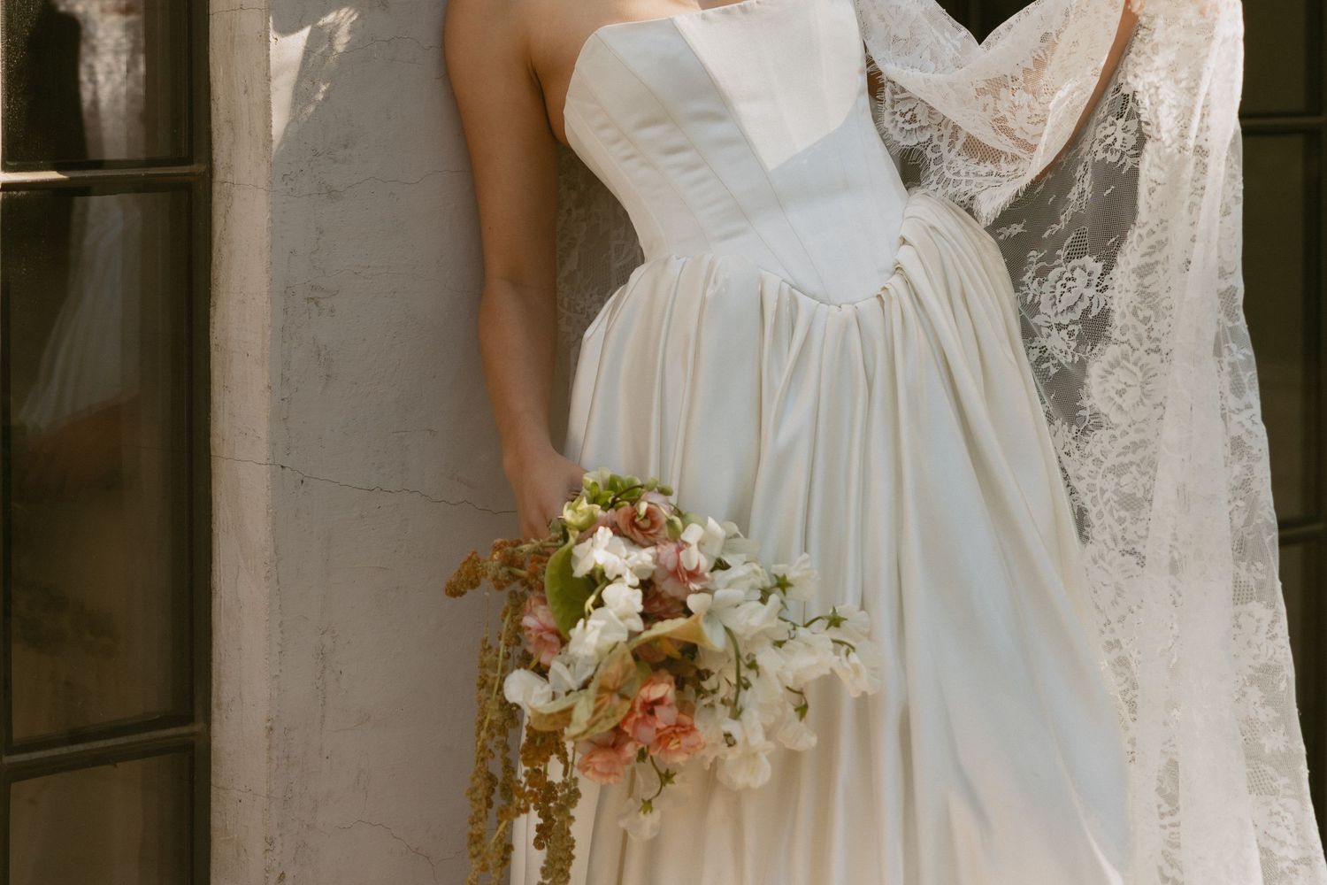 A delicate white wedding dress with a sweetheart neckline and flowy skirt, paired with a romantic peach and white bouquet.
