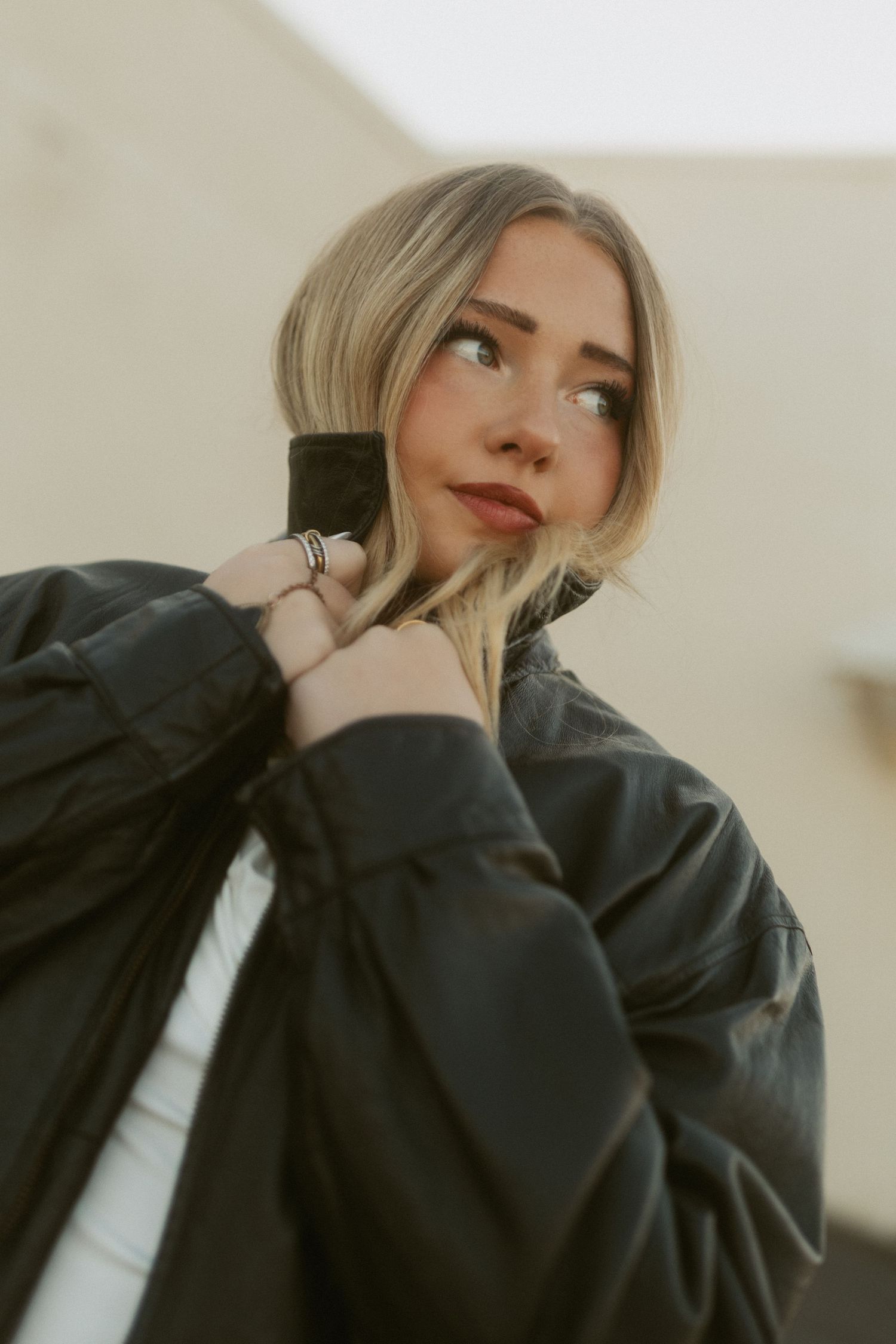 Artistic portrait series showing different poses in a black jacket against a light neutral background.