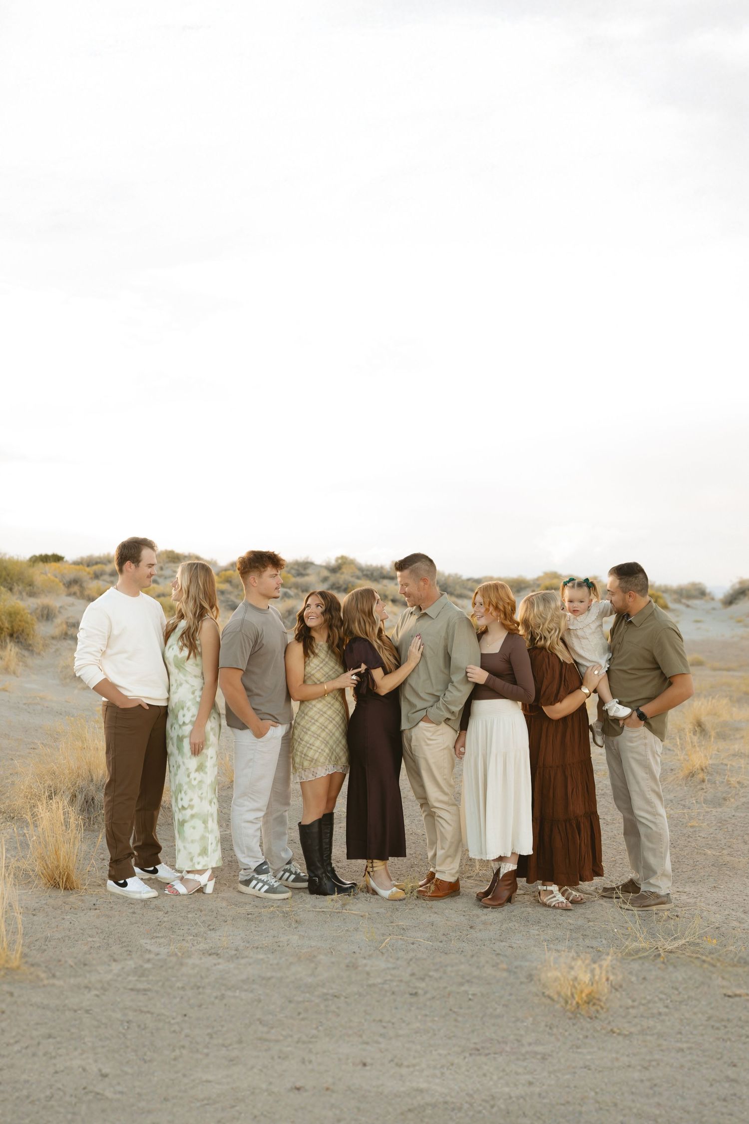 A group of people in casual attire stand together in a desert landscape during golden hour.