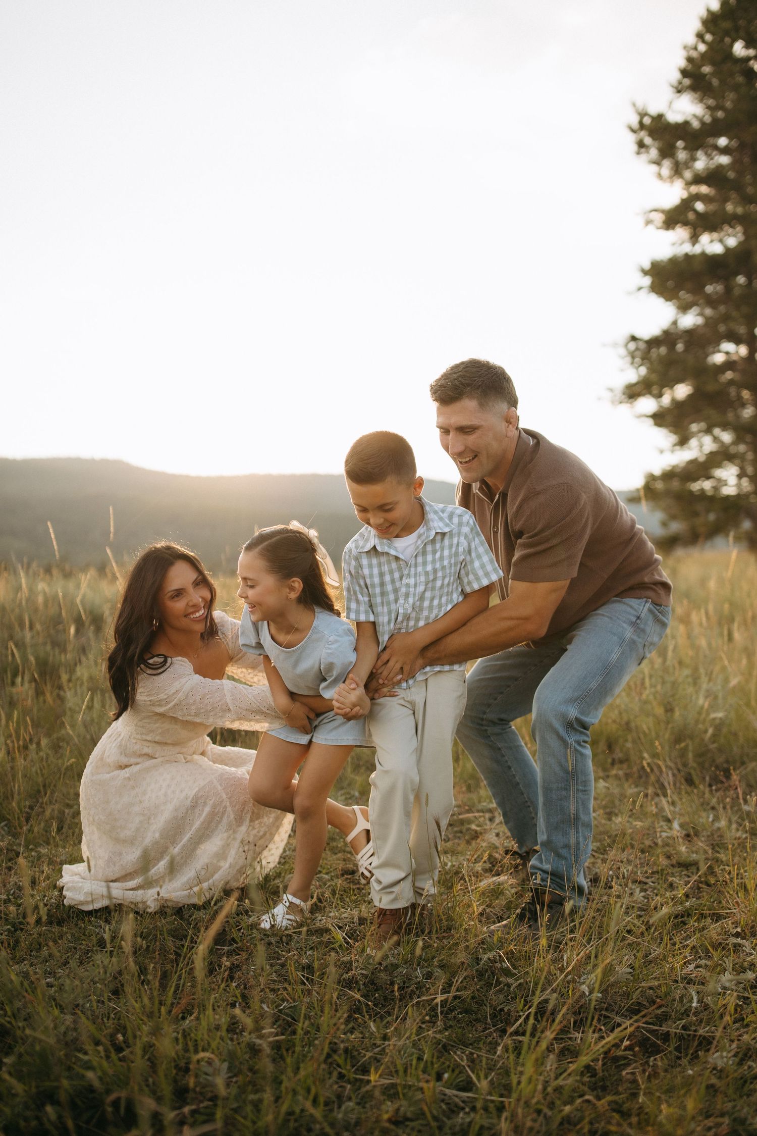 A playful family photo session in a grassy field during golden hour.