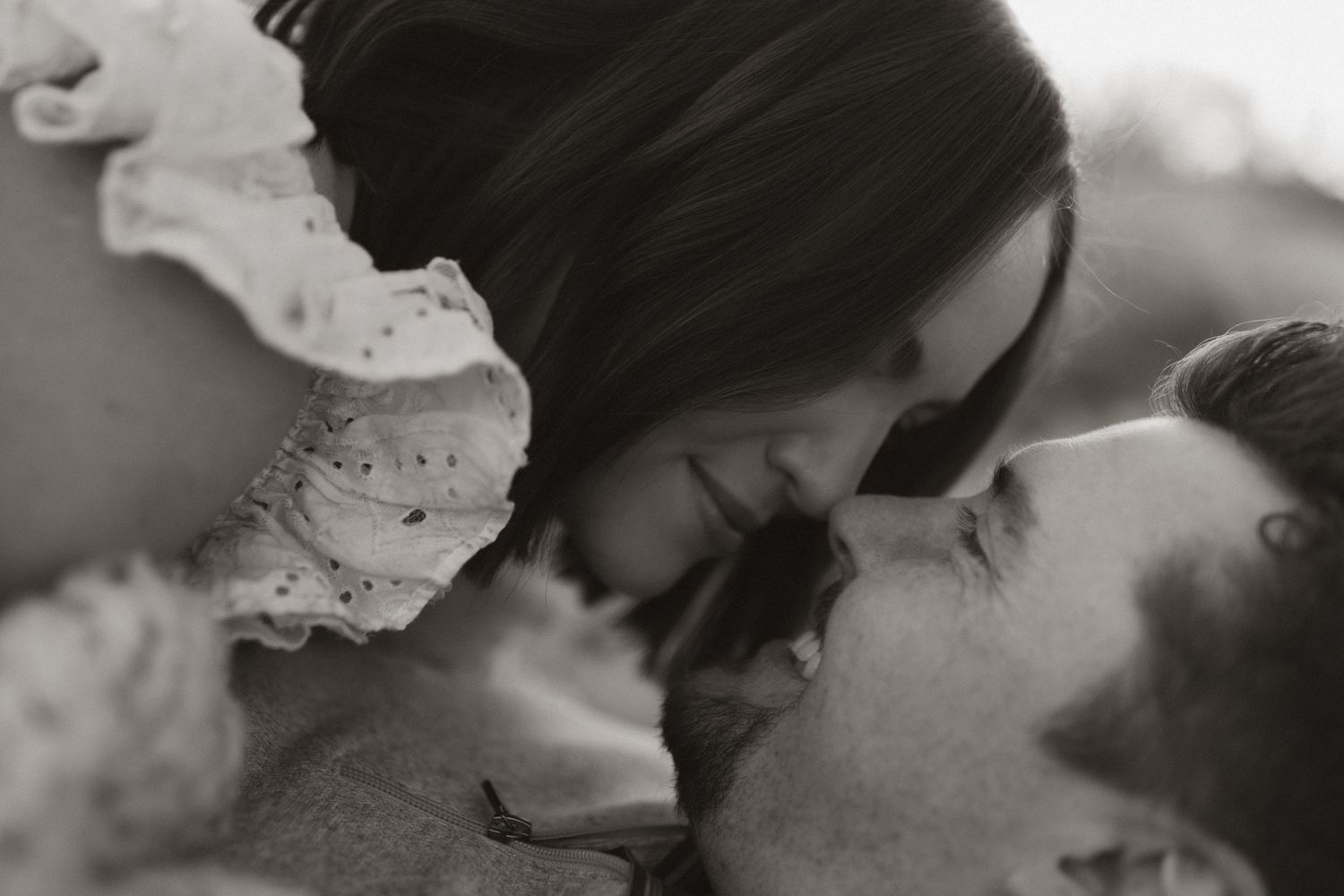 A close-up black and white photograph shows a tender moment of affection between two people.