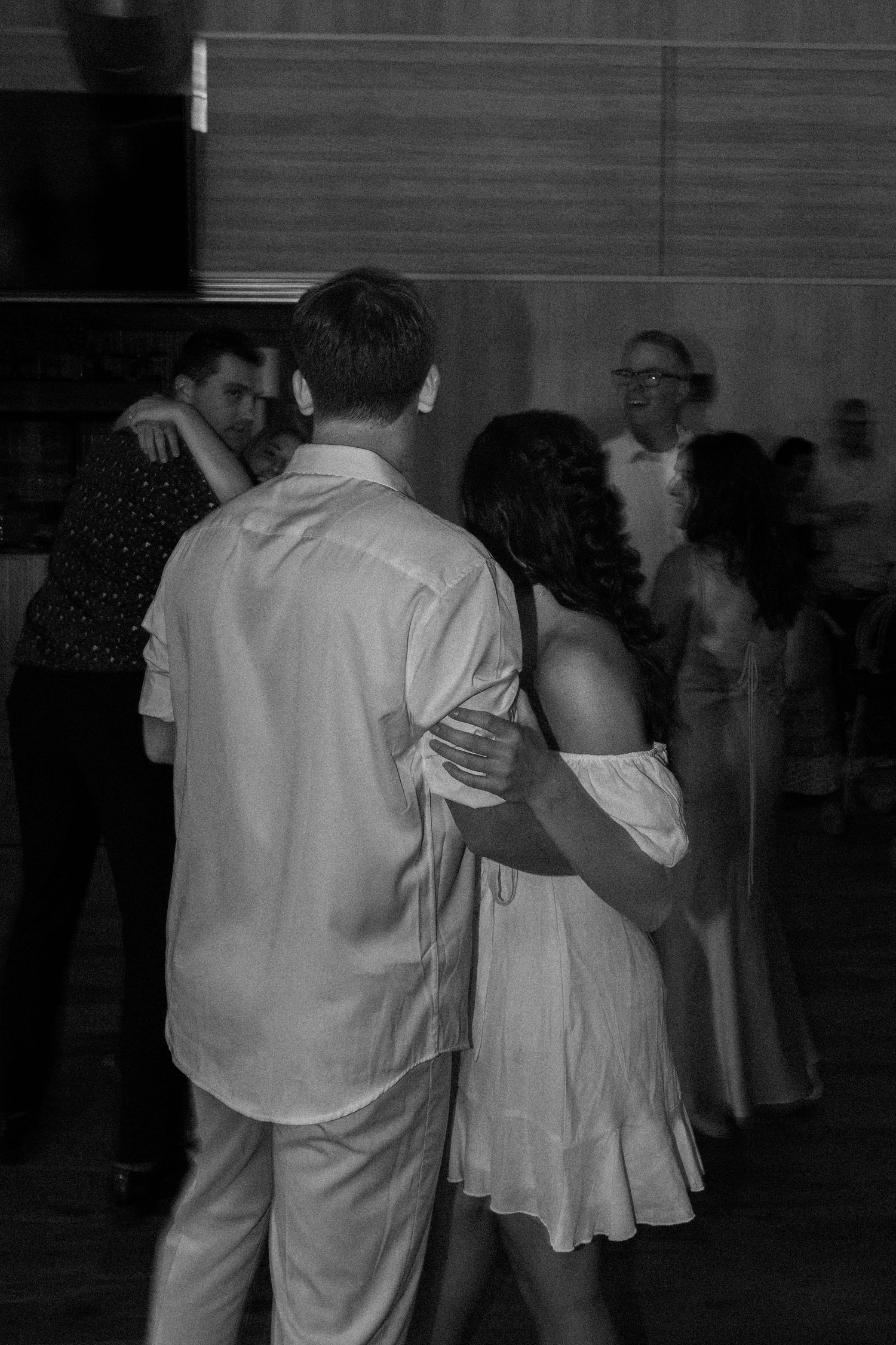 People dancing in pairs at an indoor event captured in black and white.