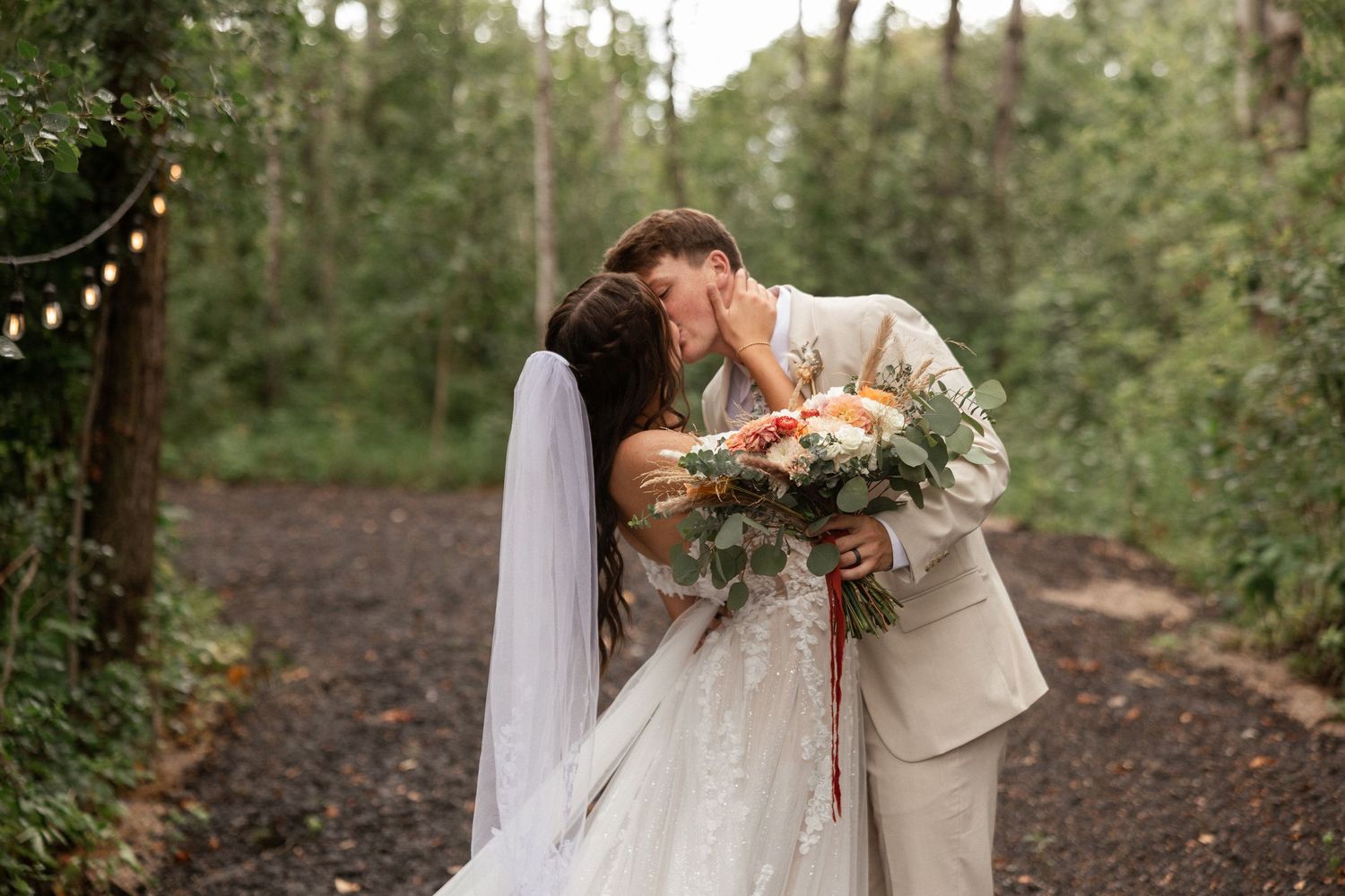 Romantic outdoor wedding photography in a wooded setting with natural lighting.