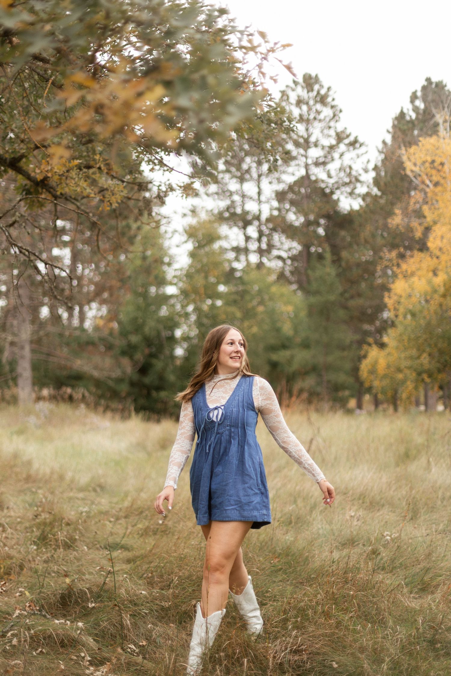 A person dances freely in a denim outfit through tall autumn grass.