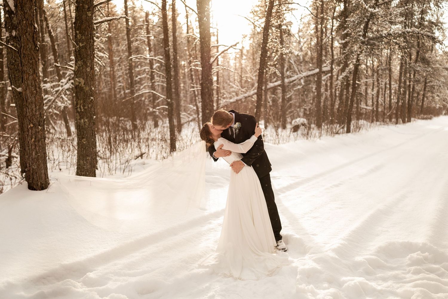 A romantic winter wedding scene with a couple embracing in a snowy forest setting.
