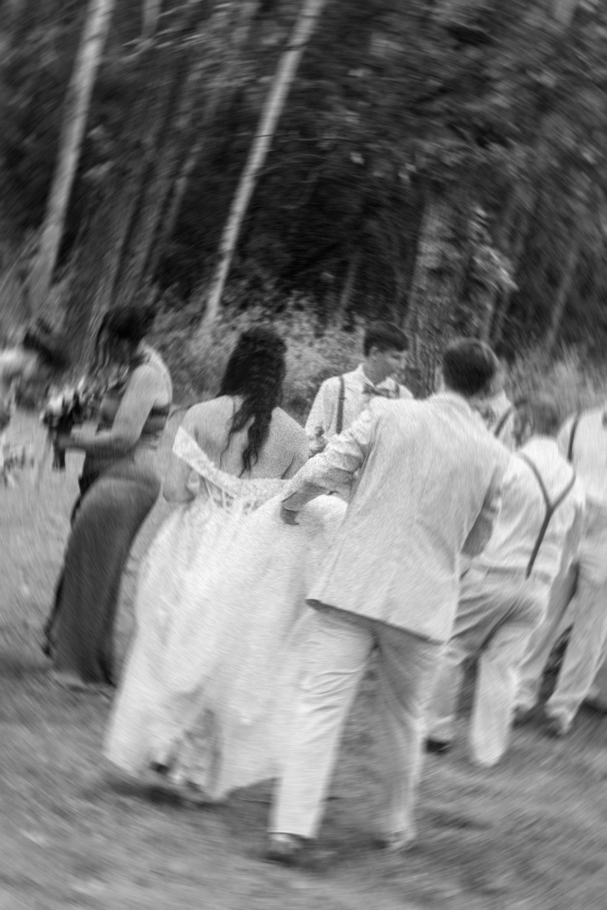 Artistic black and white motion blur of wedding party walking through woods.