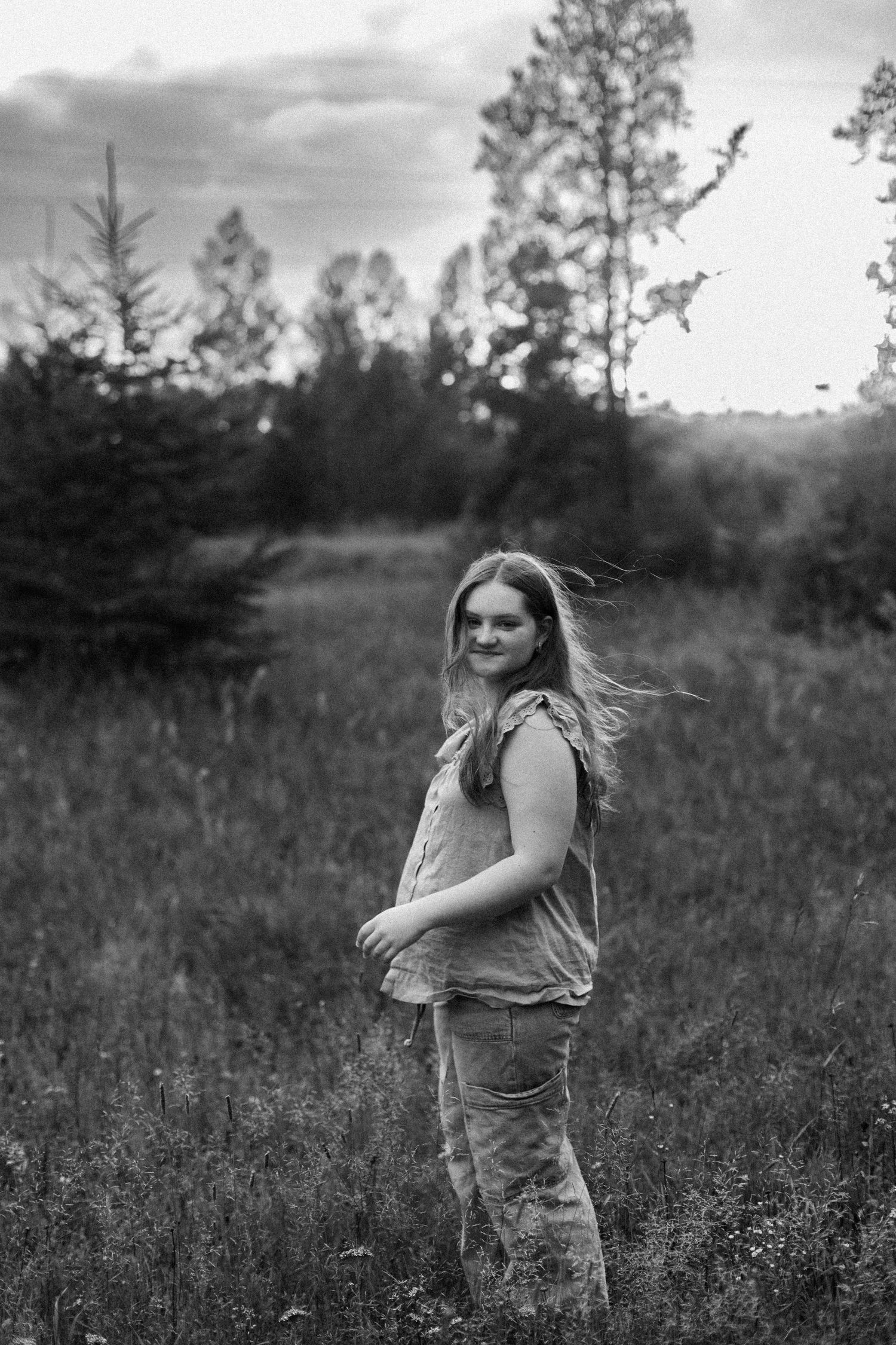 A person spins joyfully in a field during a black and white photoshoot.