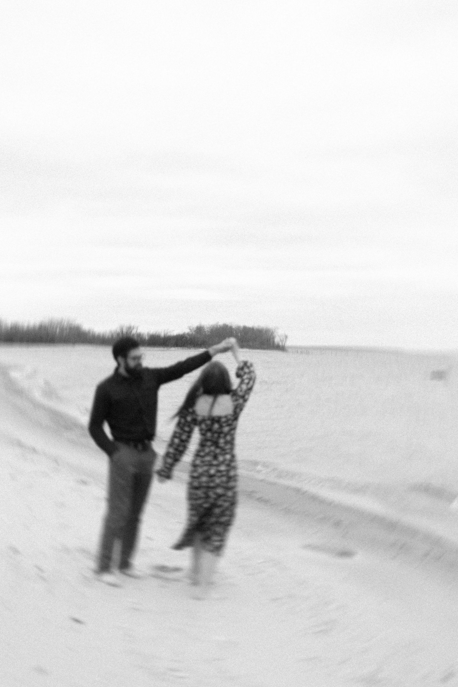 A couple plays together on a misty beach in black and white.
