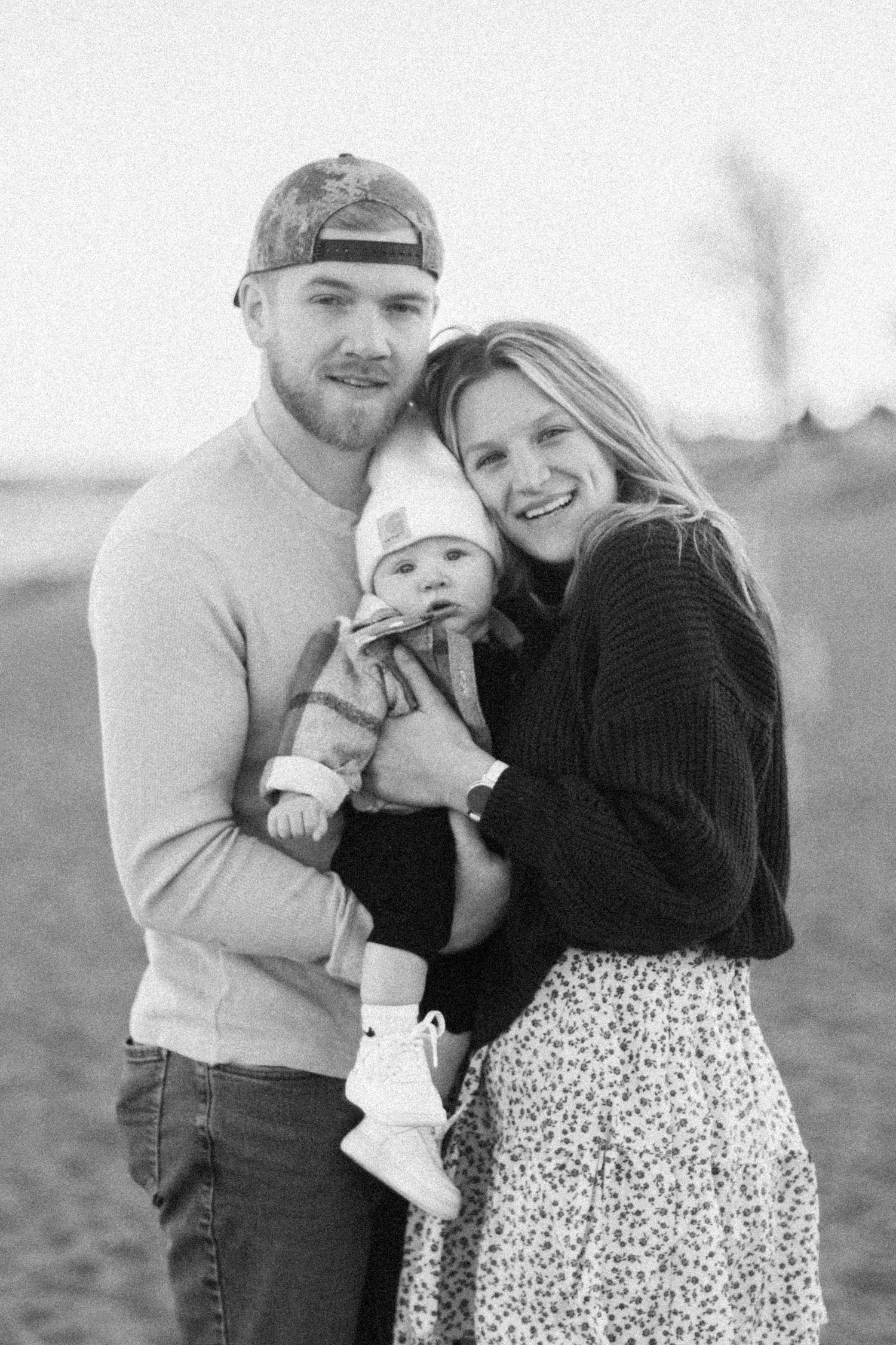 A series of three black and white romantic photos showing a couple embracing outdoors in casual winter attire.
