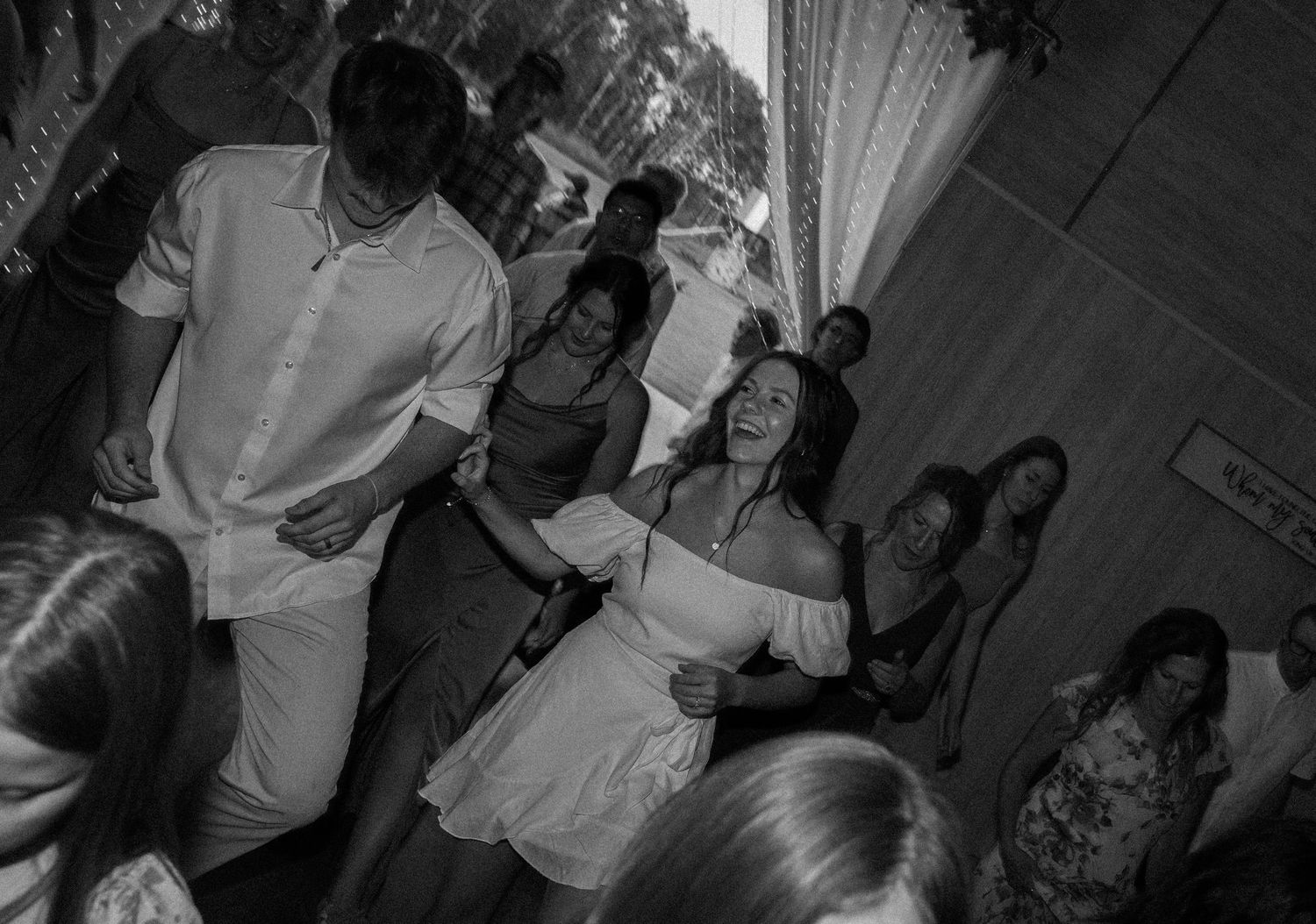 Couples dancing together at an indoor celebration in black and white.