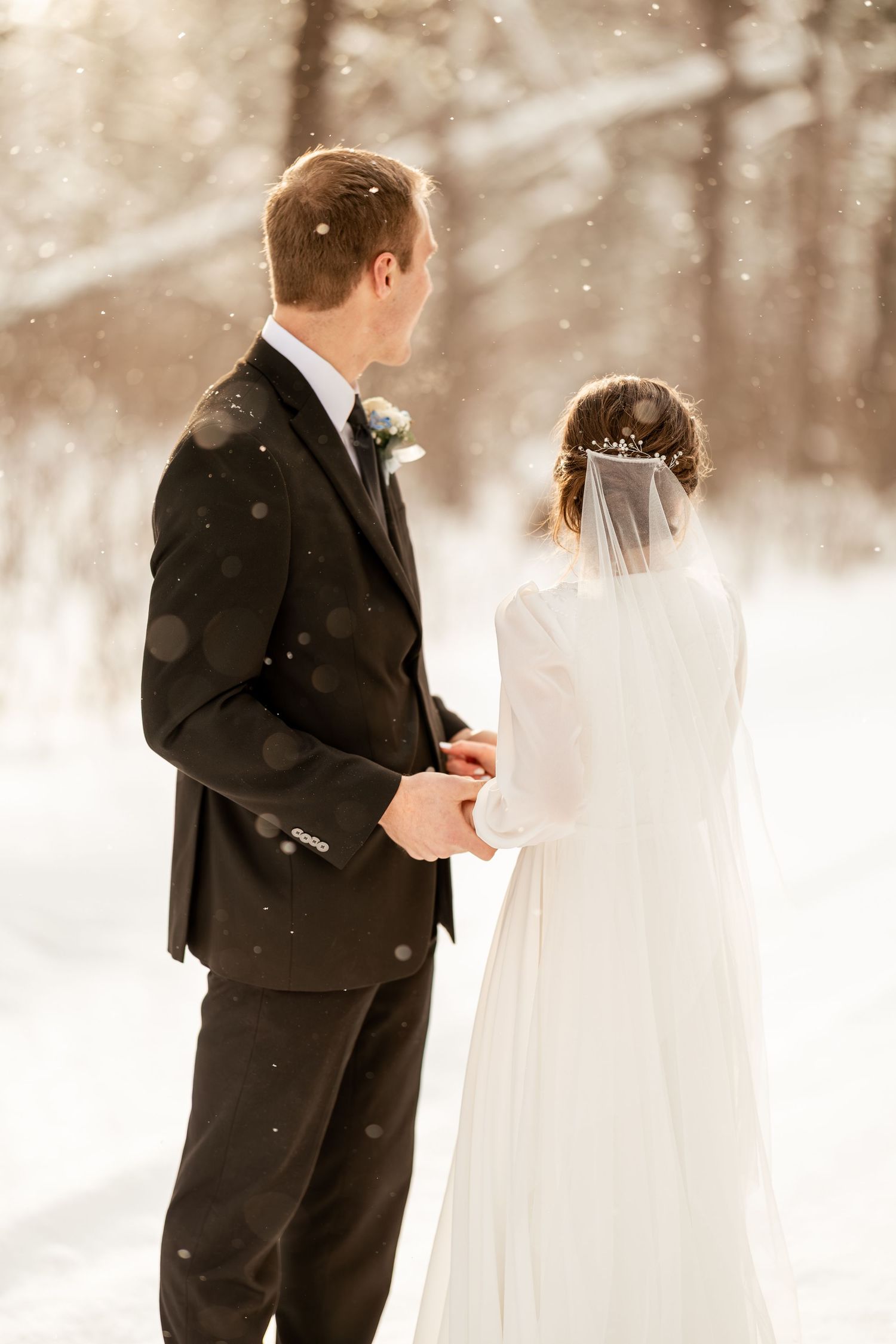 A bride and groom share a tender moment in a snowy winter landscape during their wedding photo session.