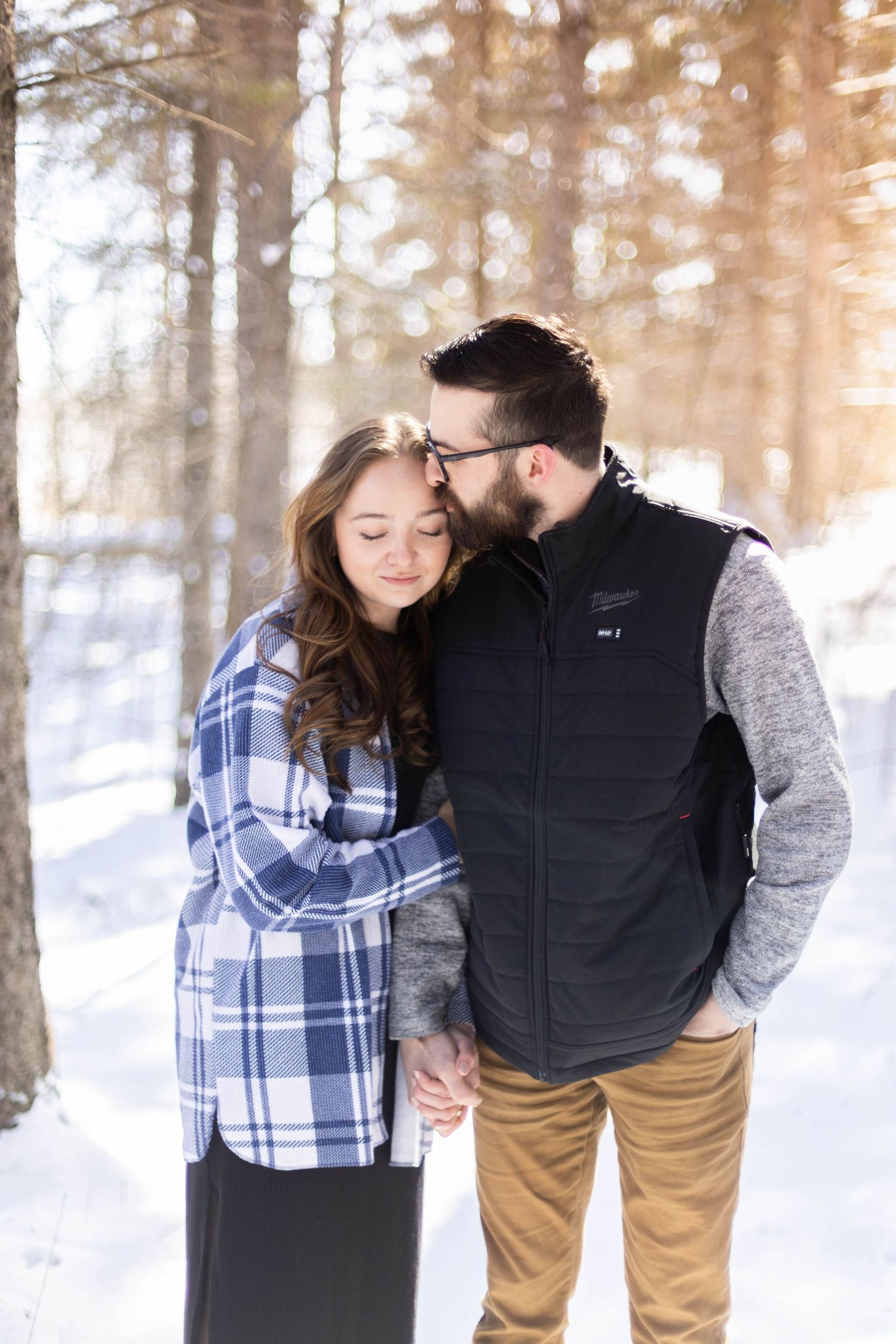 A romantic winter photoshoot with a couple in a snow-covered forest.