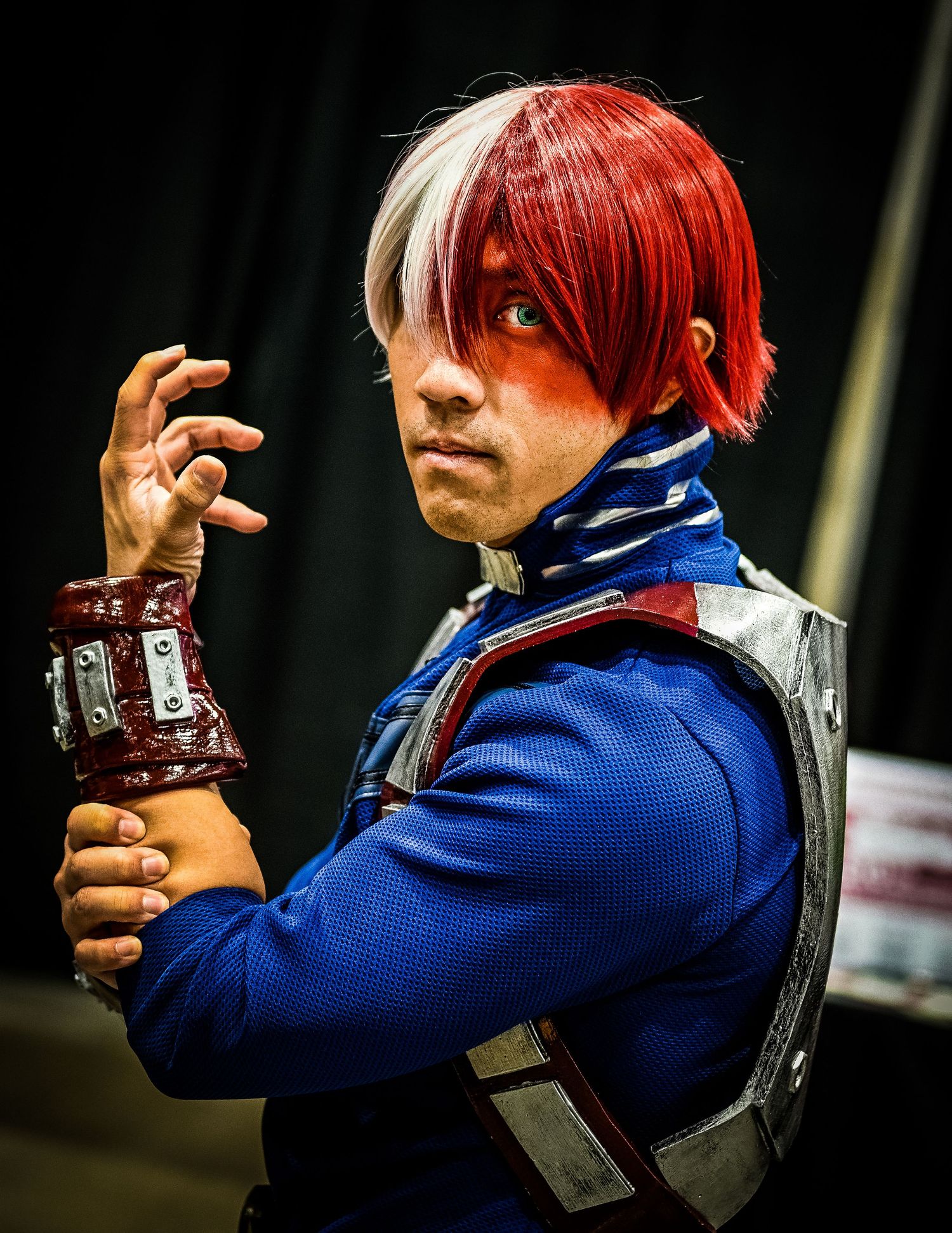 Cosplay character in blue uniform with red hair striking dramatic poses.