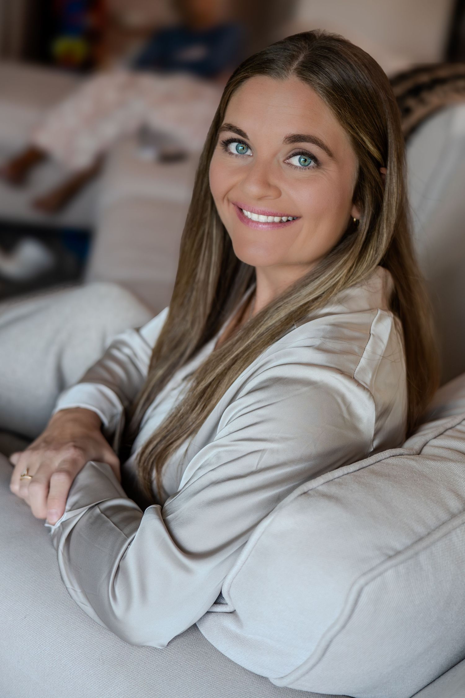 Professional portrait series showing joyful expressions while lying on a bed in a white sweater.