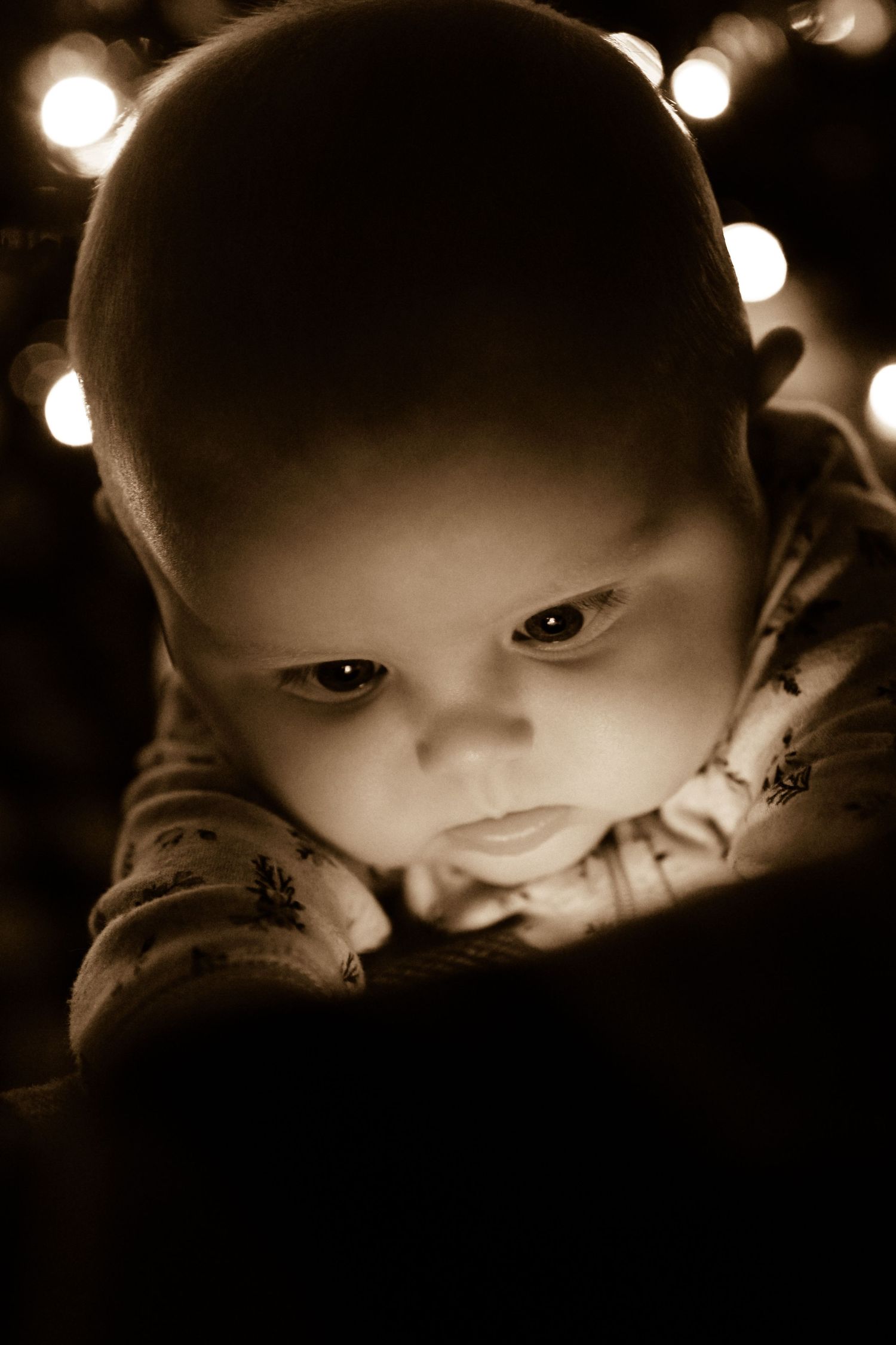 Close-up sepia portrait of baby's face in dramatic lighting.