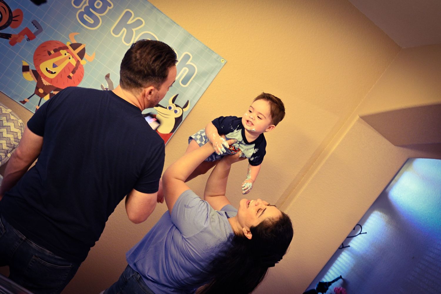 Family playtime moment captured during birthday celebration with cartoon decorations.