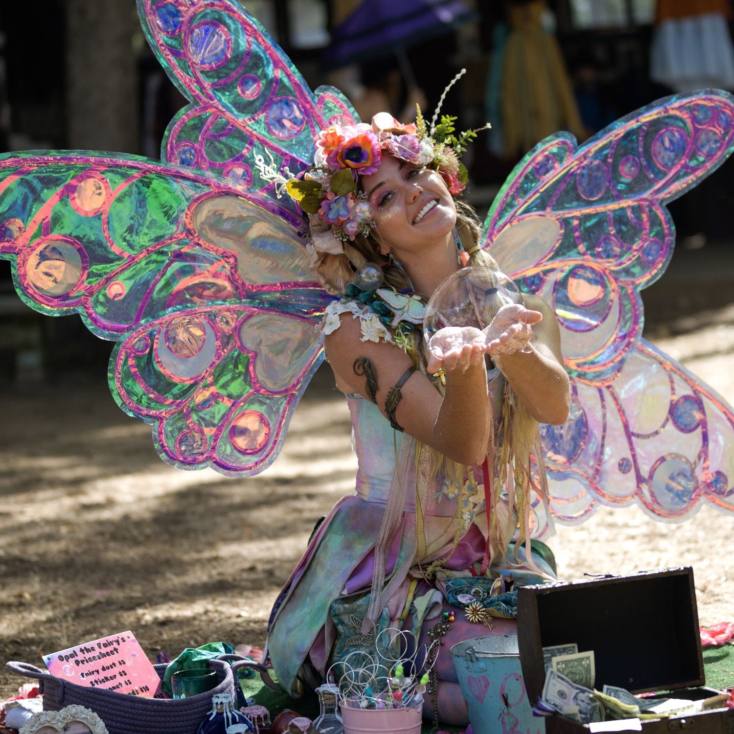 Person wearing colorful butterfly wings and costume at outdoor festival.