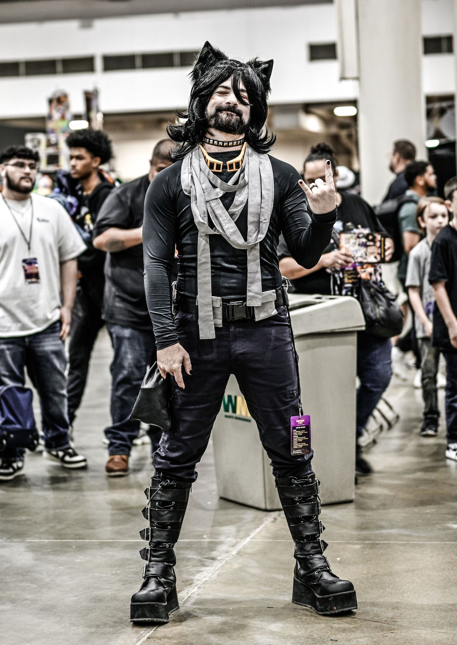 Cosplayer wearing black tactical gear and boots at indoor convention.