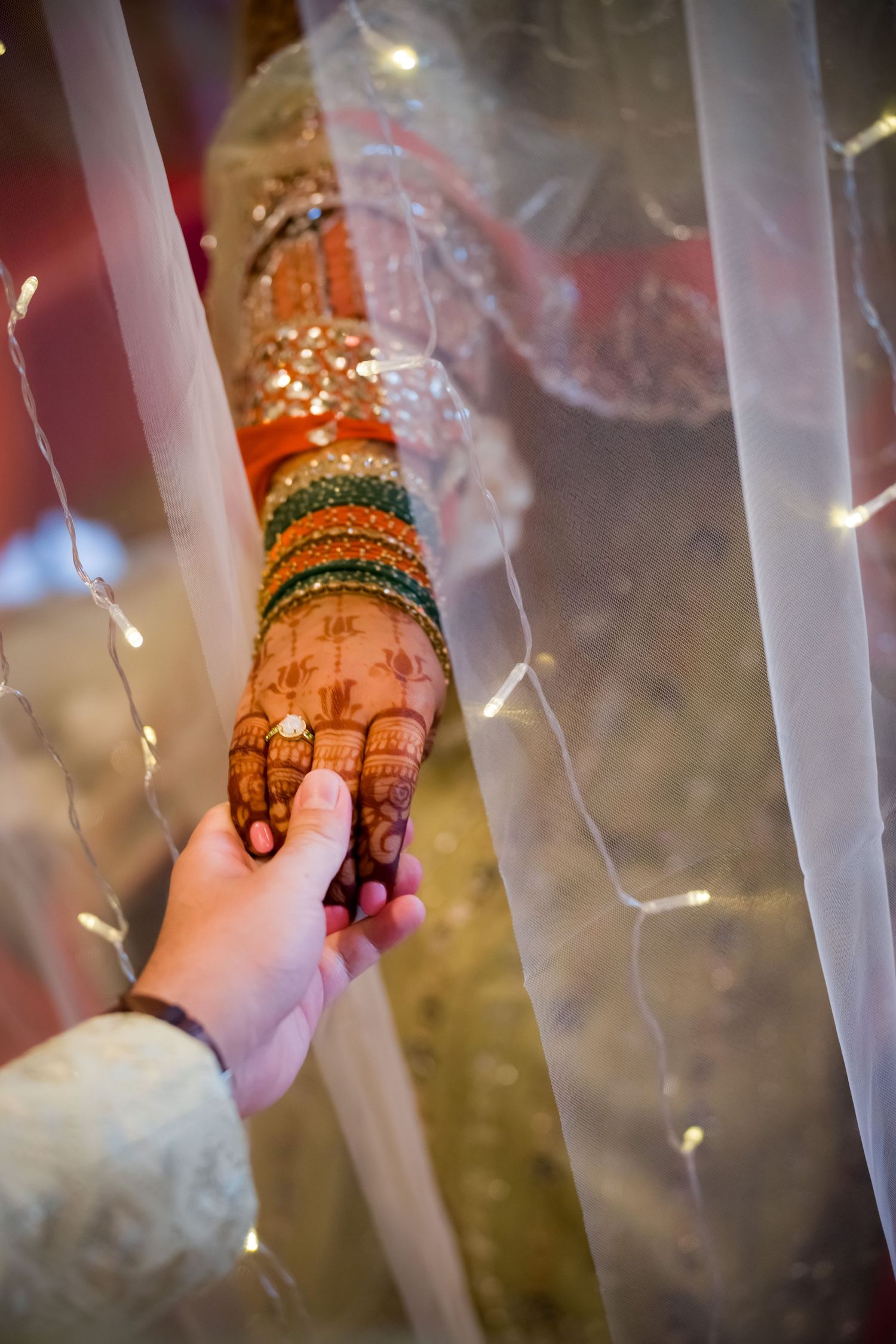 Close-up details of decorated hands with henna patterns and jewelry.