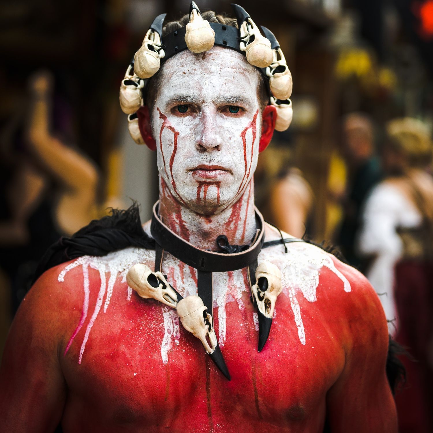 Dramatic costume makeup in white and red with decorative elements around the neck.